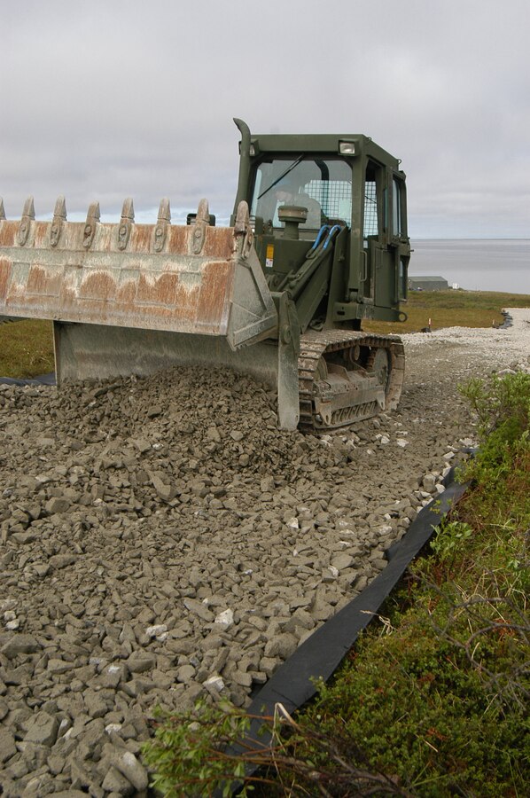 Lance Cpl. Thomas Wendt, a heavy equipment engineer with 6th Engineer Support Battalion, Battle Creek, Mich., uses a bulldozer to spread a pile of gravel to form a base for the road. Marines with 6th ESB are building a road for the village of Newtok, Alaska. The Alaskan natives in Newtok are watching their village slowly sink into the Bering Sea.
