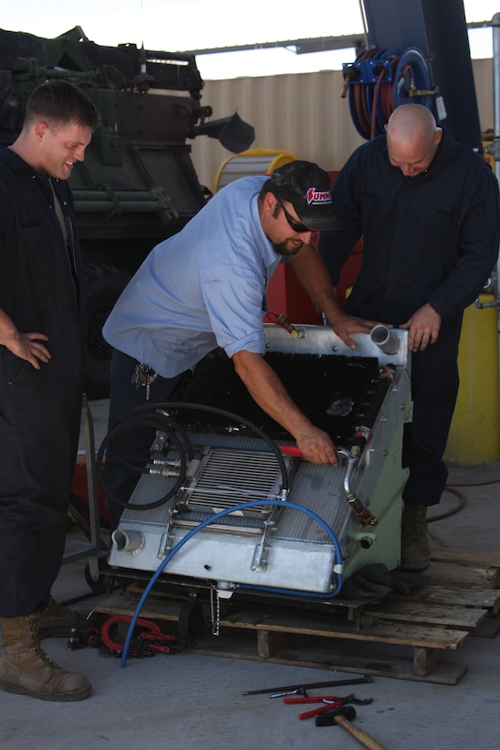 Lance Cpl. Joshua Schulte (left), Mike Matthews (center), and Pfc. Michael Dinanno, light armored vehicle mechanics with the Exercise Support Division, put new parts on LAV cooling tower, and service LAV power pack.