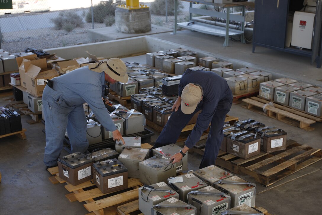John Vigar [left] and Carl Atchley, both hazardous material identifiers with the Combat Center's Hazardous Material Management Branch, inspect batteries before repairing them Tuesday at the branch's compound here.