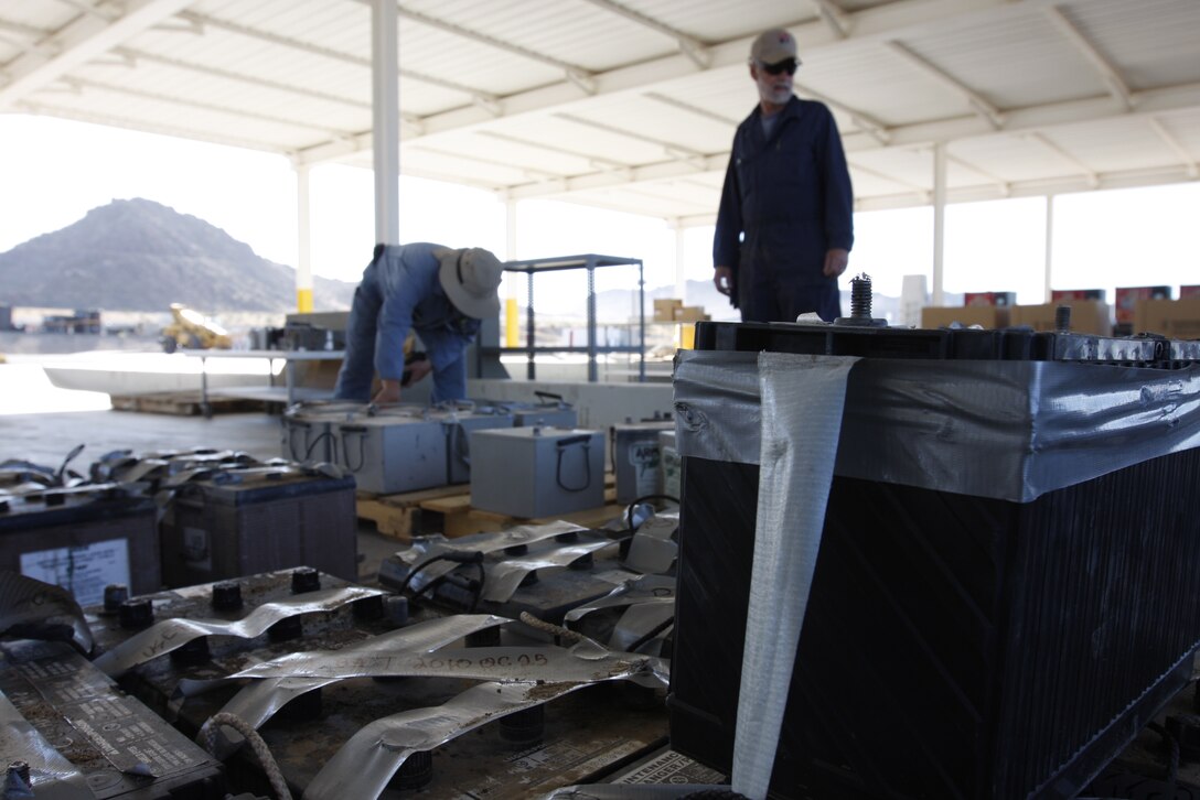 John Vigar [left] and Carl Atchley, both hazardous material identifiers with the Combat Center's Hazardous Material Management Branch, inspect batteries before repairing them Tuesday at the branch's compound here.