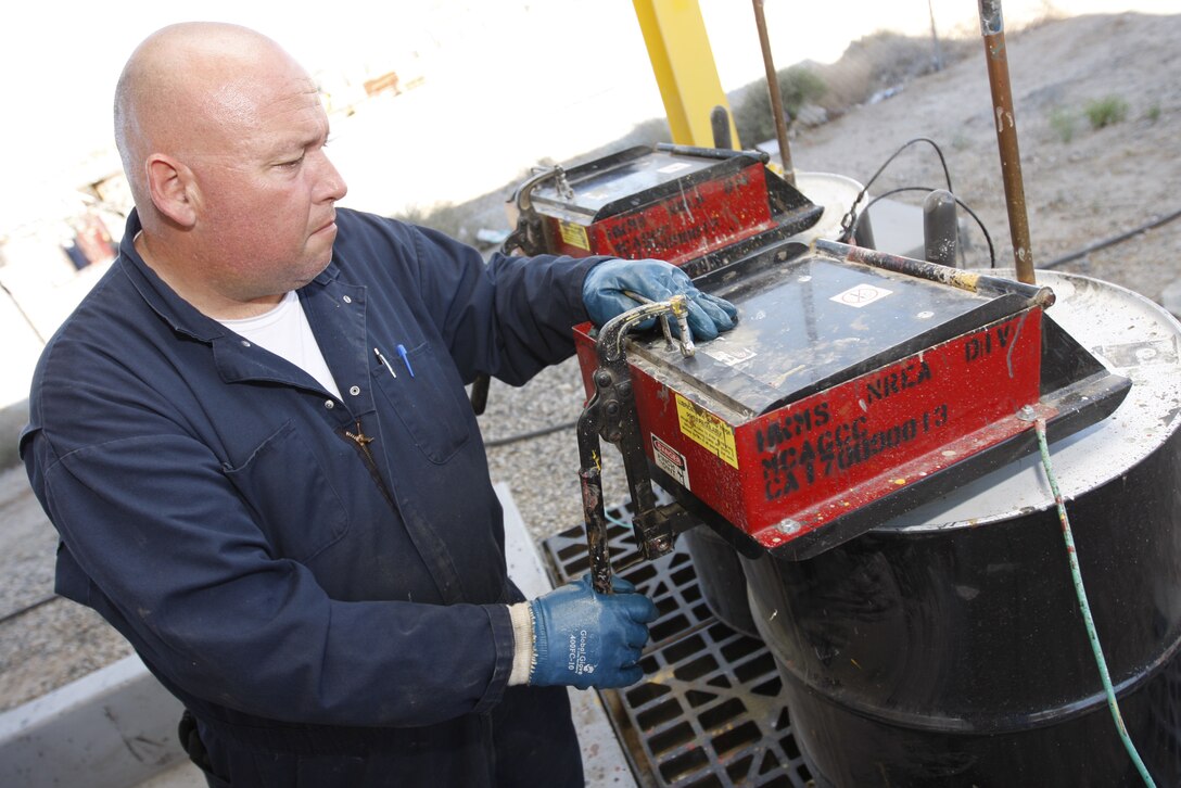 Tim Christian, a hazardous waste identifier at the Combat Center's Hazardous Waste Management Branch, expunges paint cans too empty to be saved Tuesday at the branch's compound here. Many resources collected and re-processed at the center are available free to units via the Re-Utilization program.