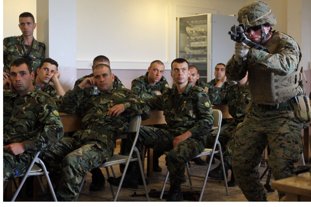 Lance Cpl. Jesse Watson, an assaultman with scout platoon, Headquarters and Service Company, 1st Tank Battalion, demonstrates a combat marksmanship stance to Bulgarian army soldiers during a class at Novo Selo Training Area, Bulgaria, June 29. The Marines have constructed an intense training schedule covering a wide variety of topics including combat marksmanship, nonlethal weapons, an introduction to the Marine Corps Martial Arts Program and convoy operations.