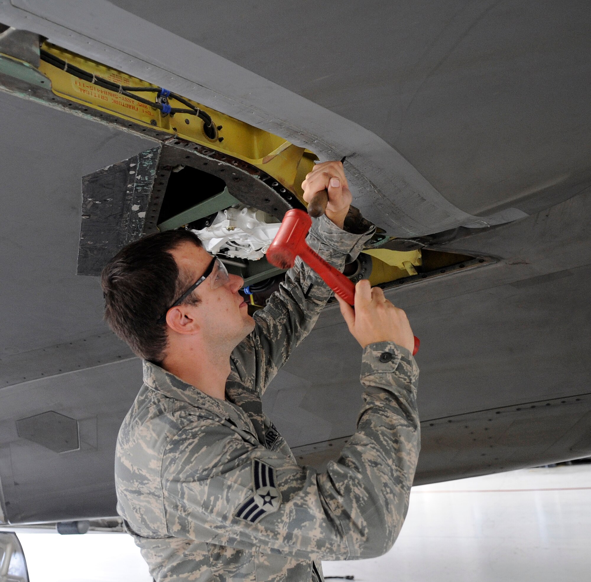 LANGLEY AIR FORCE BASE, Va. - Senior Airman Victor Sylvan, 1st Equipment Maintenance Squadron low observable aircraft structural maintenance journeyman, removes a panel from an F-22 Raptor in preparation to apply low observable coatings. Low observable is the process of a coating stack being applied on an F-22 that makes it invisible to radar, allowing the aircraft to remain undetected. (U.S. Air Force photo/Senior Airman Dana Hill)