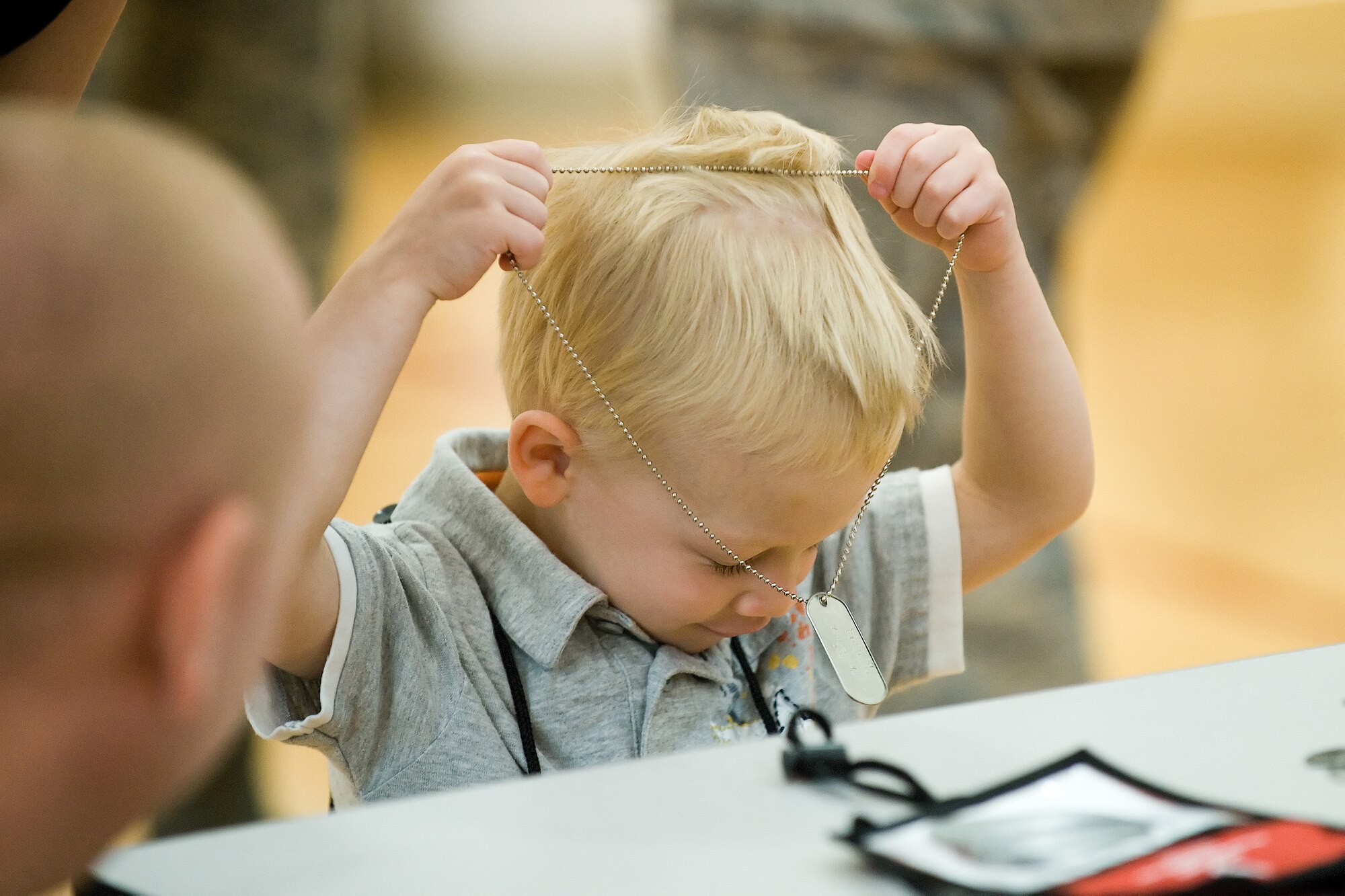 Thomas Abell Jr., 2, son of Maj. Thomas Abell, 436th Force Support Squadron, puts on his dog tags during the Children's Mobility Line June 25, 2010. The mobility line's message is children are also serving as freedom fighters while their parents are away on deployment. (U.S. Air Force photo by Jason Minto/Released)