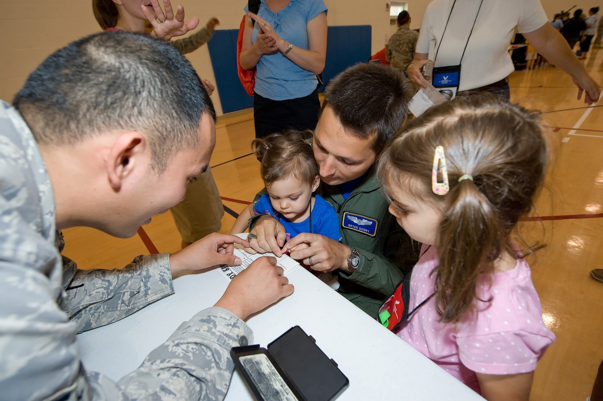 Capt. Bryan Guidry, 3rd Airlift Squadron, gets his daughters', Jeanette, 2, and Acadia, 4, finger prints during the Children's Mobility Line June 25, 2010. The Children's Mobility Line was put in place to help show children what their parents go through during the pre-deployment process and help relieve some of the stress. (U.S. Air Force photo by Jason Minto/Released)