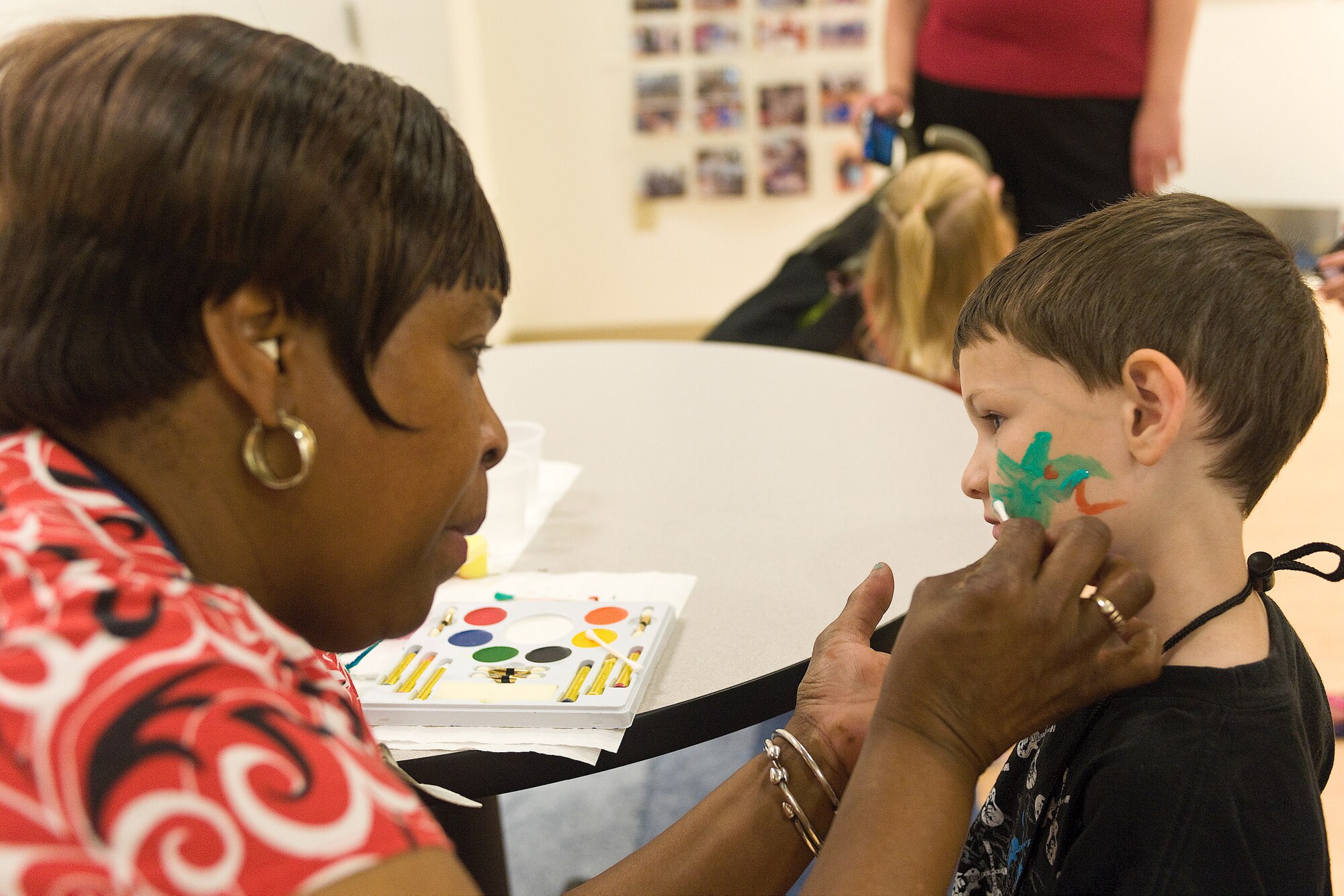 Patricia Edwards, 436th Force Support Squadron, paints faces during the Children's Mobility Line June 25, 2010. The mobility line shows the children they are important to the mission as well and that they serve too while their parents are away. (U.S. Air Force photo by Roland Balik/Released)