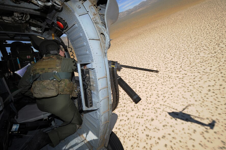 Staff Sgt. Andrew Gibson, scans terrain for training targets from an HH-60 Pave Hawk helicopter during a fixed, forward firing mission over the Nevada Test and Training Ranges on 25 June, 2010. Sgt. Gibson is a flight engineer assigned to the 129th Rescue Squadron, Moffett Field, Calif.  (U.S. Air Force photo by Master Sgt. Kevin Gruenwald/Released)