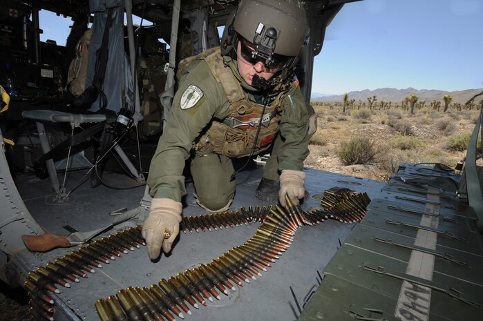 Staff Sgt. Andrew Gibson, gathers .50-caliber machine gun ammo on board an HH-60G Pave Hawk helicopter during a fixed, forward firing mission over the Nevada Test and Training Ranges on 25 June, 2010. Sgt. Gibson is a flight engineer assigned to the 129th Rescue Squadron, Moffett Field, Calif.  (U.S. Air Force photo by Master Sgt. Kevin Gruenwald/Released)