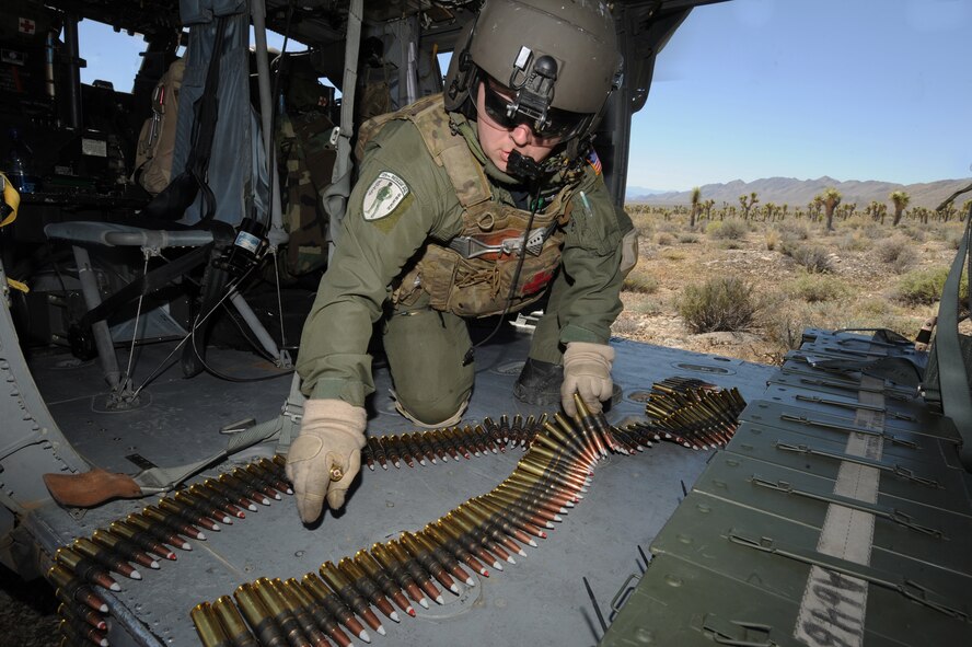 Staff Sgt. Andrew Gibson, gathers .50-caliber machine gun ammo on board an HH-60G Pave Hawk helicopter during a fixed, forward firing mission over the Nevada Test and Training Ranges on 25 June, 2010. Sgt. Gibson is a flight engineer assigned to the 129th Rescue Squadron, Moffett Field, Calif.  (U.S. Air Force photo by Master Sgt. Kevin Gruenwald/Released)