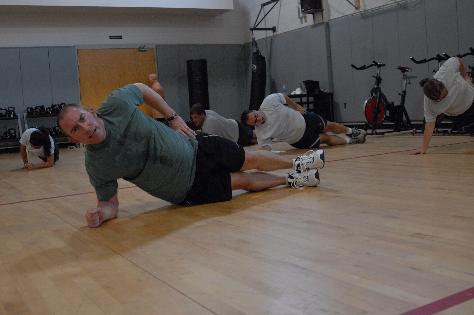 Brent Cowen, an exercise physiologist with Hurlburt Field's Health and Wellness Center, leads the Boot Camp class in doing oblique flanks at the Aderholt Fitness Center, Hurlburt Field, Fla., June 24, 2010. The Hurlburt Field Boot Camp, run by the base’s Health and Wellness Center, is a base-unique program that takes Airmen with marginal or failing scores through 80 days of intense physical training. (DoD photo by U.S. Air Force Staff Sgt. Orly N. Tyrell/Released)