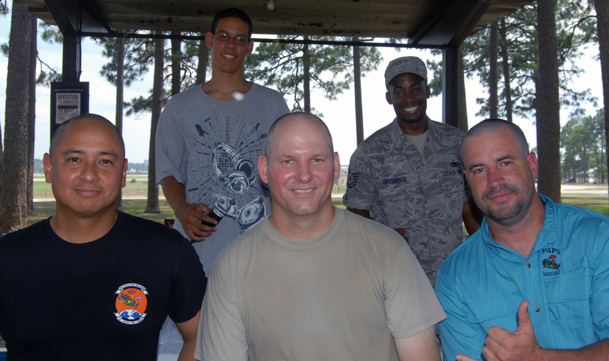 Lt. Col. Frank Flores, 3rd Aerial Port Commander (bottom left), Chief Master Sgt. Patton Scales (bottom middle), 3rd APS superintendent and Edwin Byrnes (bottom right), 3rd APS assistant director of operations shaved their heads during a squadron picnic June 24 at Woodland Park, here. The group shaved their heads in recognition of the 3rd APS receipt of an “outstanding” during a recent inspection. (U.S. Photo/ 1st Lt. Cammie Quinn)

