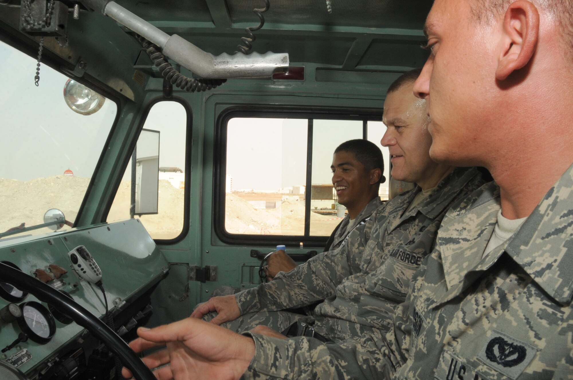 Senior Airman Joshua Thompson, 380 Expeditionary Civil Engineer Squadron, fire fighter driver operator, explains the operation of a P-19 crash fire truck to Chief Master Sgt. of the Air Force James A. Roy and Staff Sgt. Delavar McKee June 27 at an undisclosed base in Southwest Asia. Chief Roy was here as part of as part of his tour of bases in the U.S. Central Command area of responsibility. (U.S. Air Force photo/ Tech. Sgt. April Wickes)