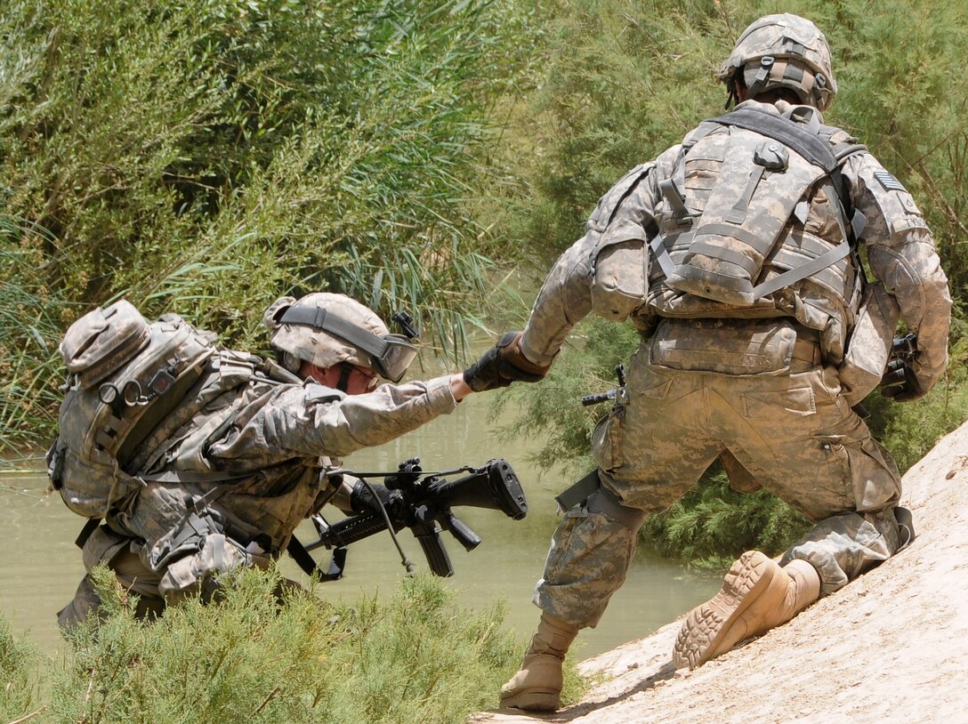 U.S. Army Pfc. Erik Tyson, right, helps Pfc. Steven Price up after crossing a creek while on patrol in Zabul province, Afghanistan, June 25, 2010. Tyson and Price are assigned to Company D, 1st Battalion, 4th Infantry Regiment.