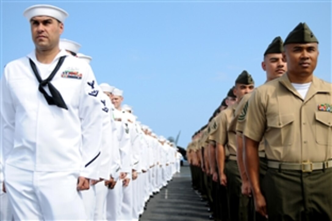 Sailors and Marines of the USS Ronald Reagan stand at attention before manning the rails on the flight deck in Pearl Harbor, Hawaii, June 28, 2010. 