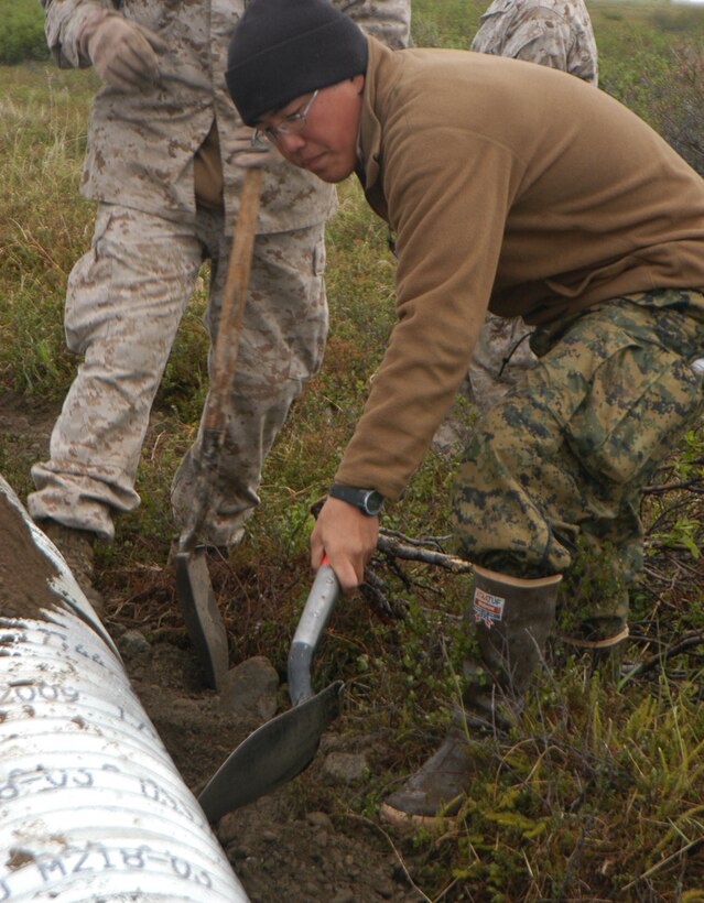 Lance Cpl. Euiseok Kim, a member of the 6th Engineer Support Battalion road team, Battle Creek, Mich., spreads dirt over a culvert. Culverts are used to protect the road. from water damage from melting snow.