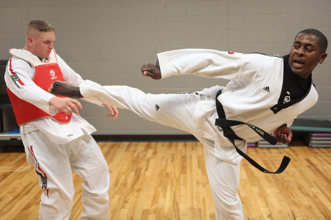Cpl. Michael King, an administrative assistant to the chaplain of the Marine Corps, knocks back Cpl. Waylon Parker while performing a powerful side kick at the Joint Base Myer-Henderson Hall gym in Arlington, Va., June 30. King is a second degree black belt in tae kwon do.