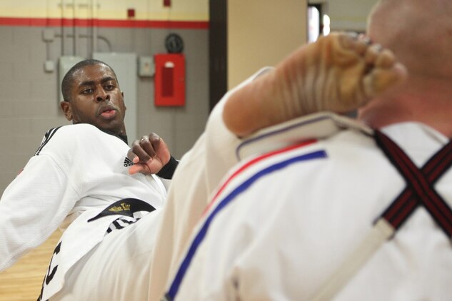 Cpl. Michael King, administrative assistant to the chaplain of the Marine Corps, performs a high turning kick on Cpl. Waylon Parker at the Joint Base Myer-Henderson Hall gym in Arlington, Va., June 30. King executed this kick to demonstrate the flexibility and practice required for tae kwon do.