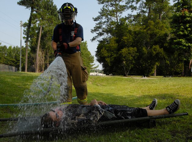 A member of Joint Team Charleston is hosed down by Jeff Feltner while playing the role of a casualty during a mass casualty exercise on Joint Base Charleston, S.C., June 25, 2010. The exercise simulated 100 casualties that occurred as a result of a simulated explosion near a base softball field. Eighty-six of the casualties were played by Sailors from the Naval Weapons Station. Mr. Feltner is a fire captain with the 628th Civil Engineer Squadron. (U.S. Air Force Photo/Airman 1st Class Lauren Main)