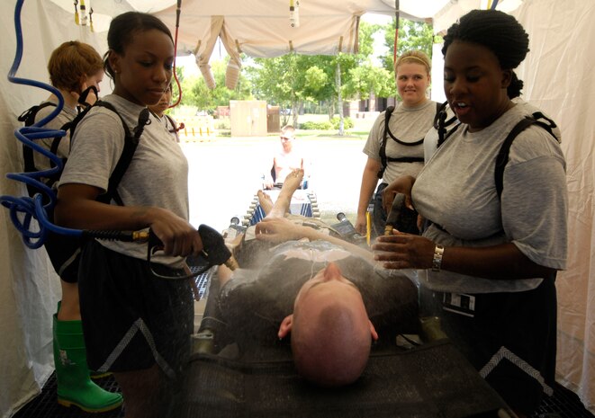 Airmen with the 628th Medical Group decontaminate a victim during a mass casualty exercise held on Joint Base Charleston, S.C., June 25, 2010. The exercise simulated the explosion of a ?dirty bomb? at a base softball field which caused 100 simulated casualties. A dirty bomb is a chemical-type weapon that combines radioactive material with conventional explosives. The weapon contaminates the area around the explosion with radioactive material. (U.S. Air Force Photo/Airman 1st Class Lauren Main)