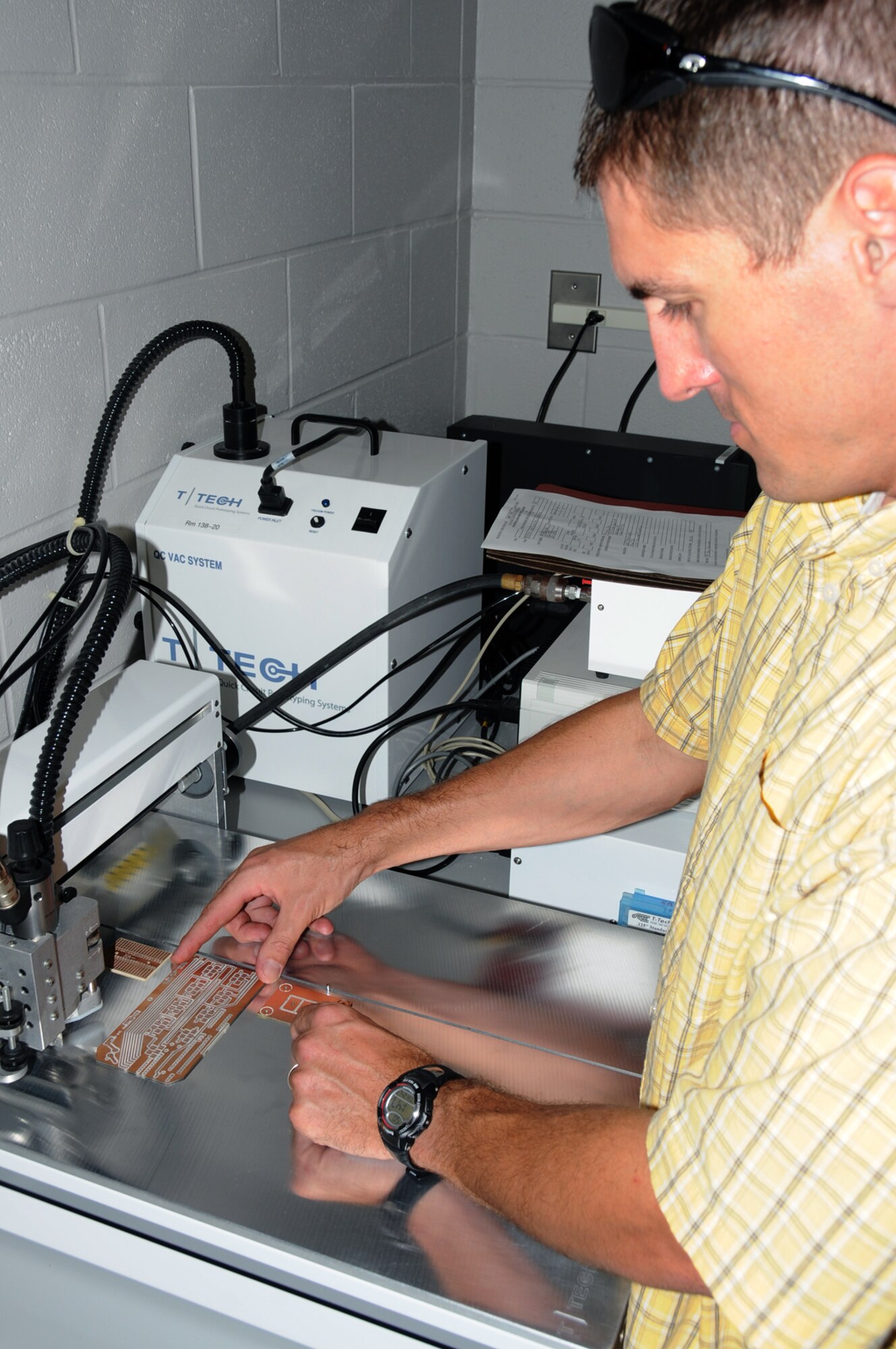 Metal trades supervisor Tomme Lassabe sets up  the circuit router to design circuit cards.  (U.S. Air Force photo by Kemberly Groue)