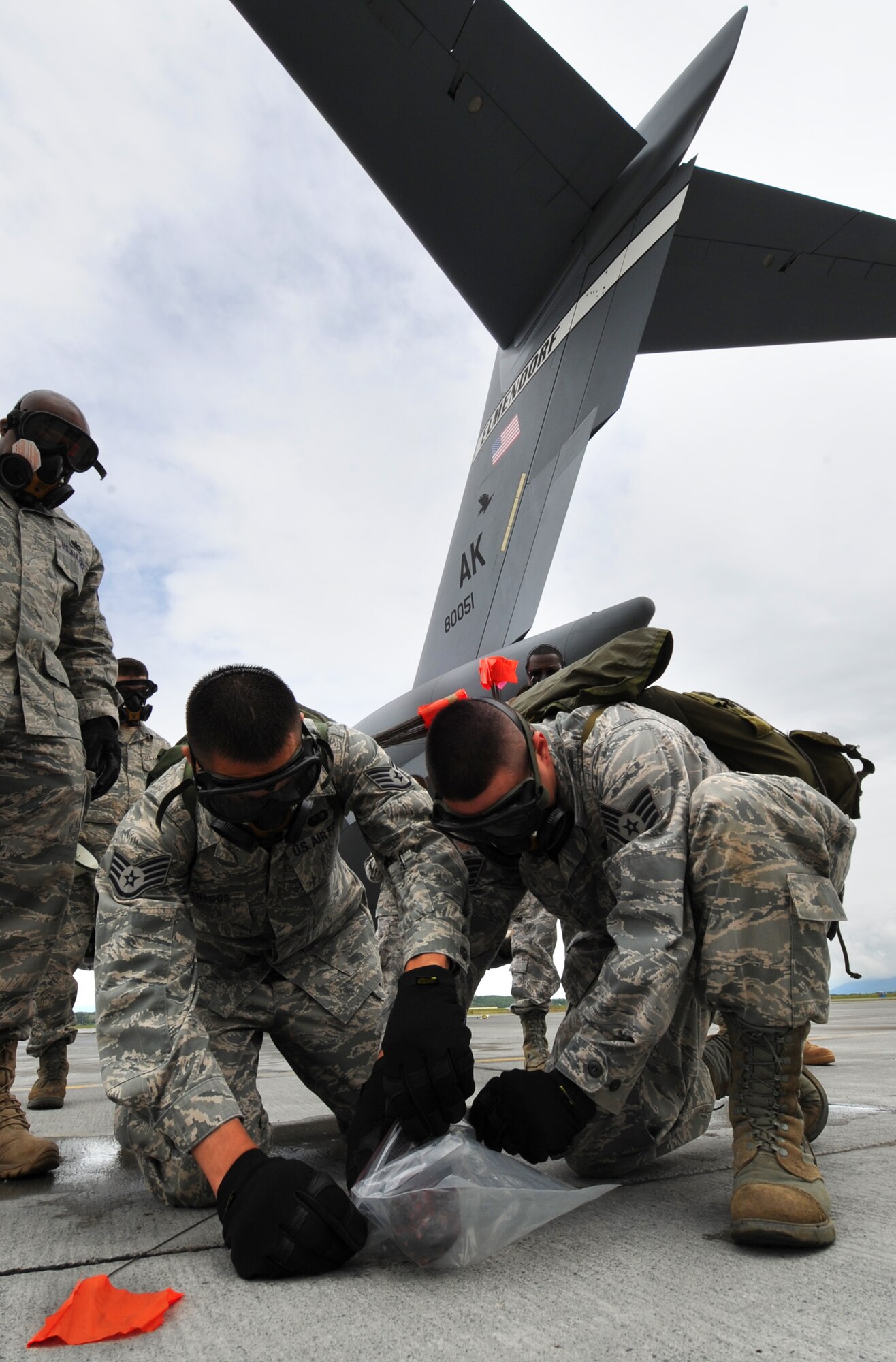 Members of the 3rd Force Support Squadron's search and recovery team bag a simulated body part that was found at the accident scene during the emergency management exercise at Joint Base Elmendorf-Richardson, June 29. During the search and recovery portion of an exercise, players practice searching and recording human remains or belongings after an accident. (Air Force photo by Senior Airman Cynthia Spalding)