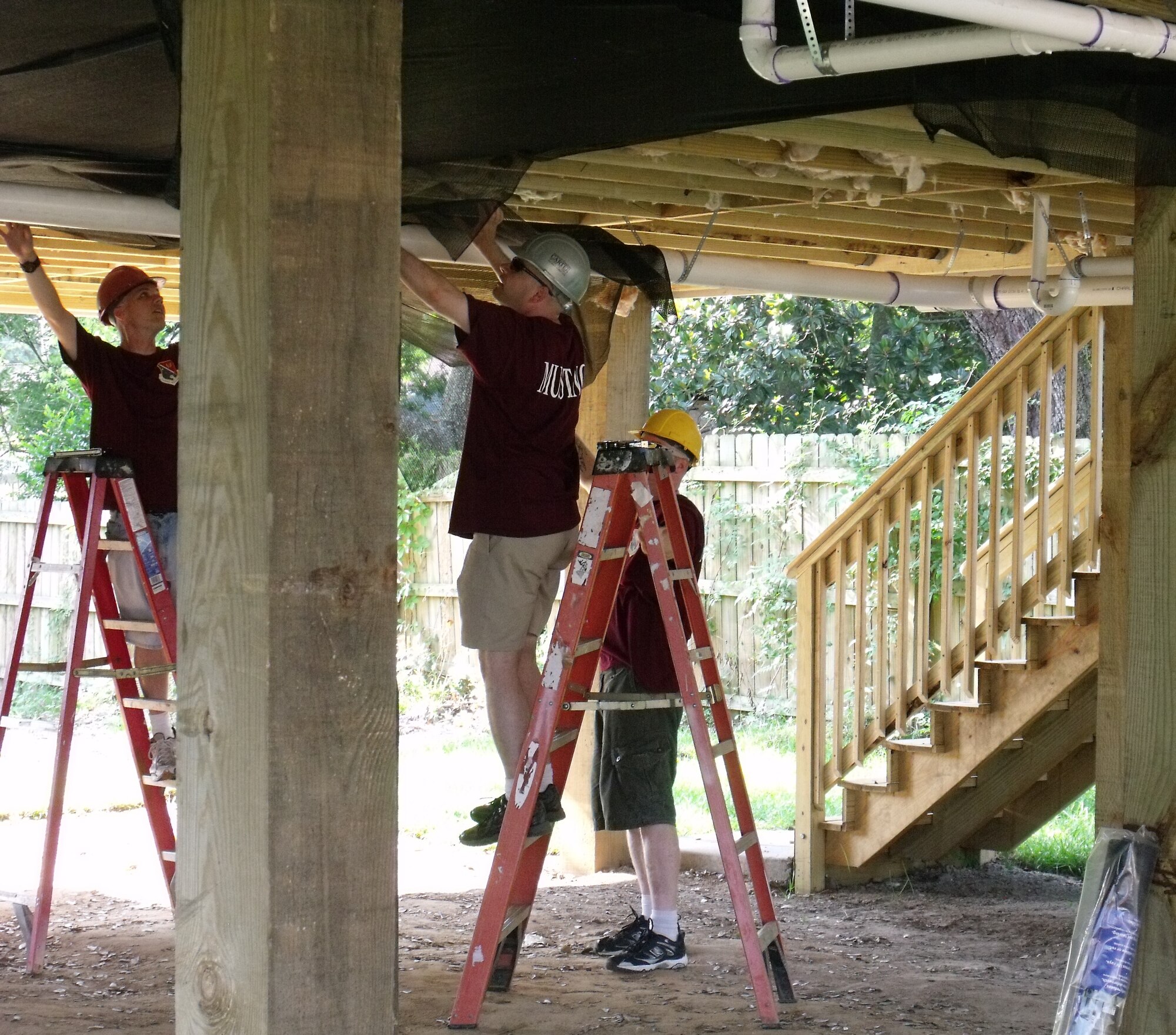 Tech. Sgts Shannon Smith, Travis AFB, Calif; and James Butler and Mark Liston, Minot AFB, N.D. hang insulation under a raised home being built in a Biloxi neighborhood that was ravaged by Hurricane Katrina’s storm surge.  (U.S. Air Force photo by Tech. Sgt. Mark Jegel)