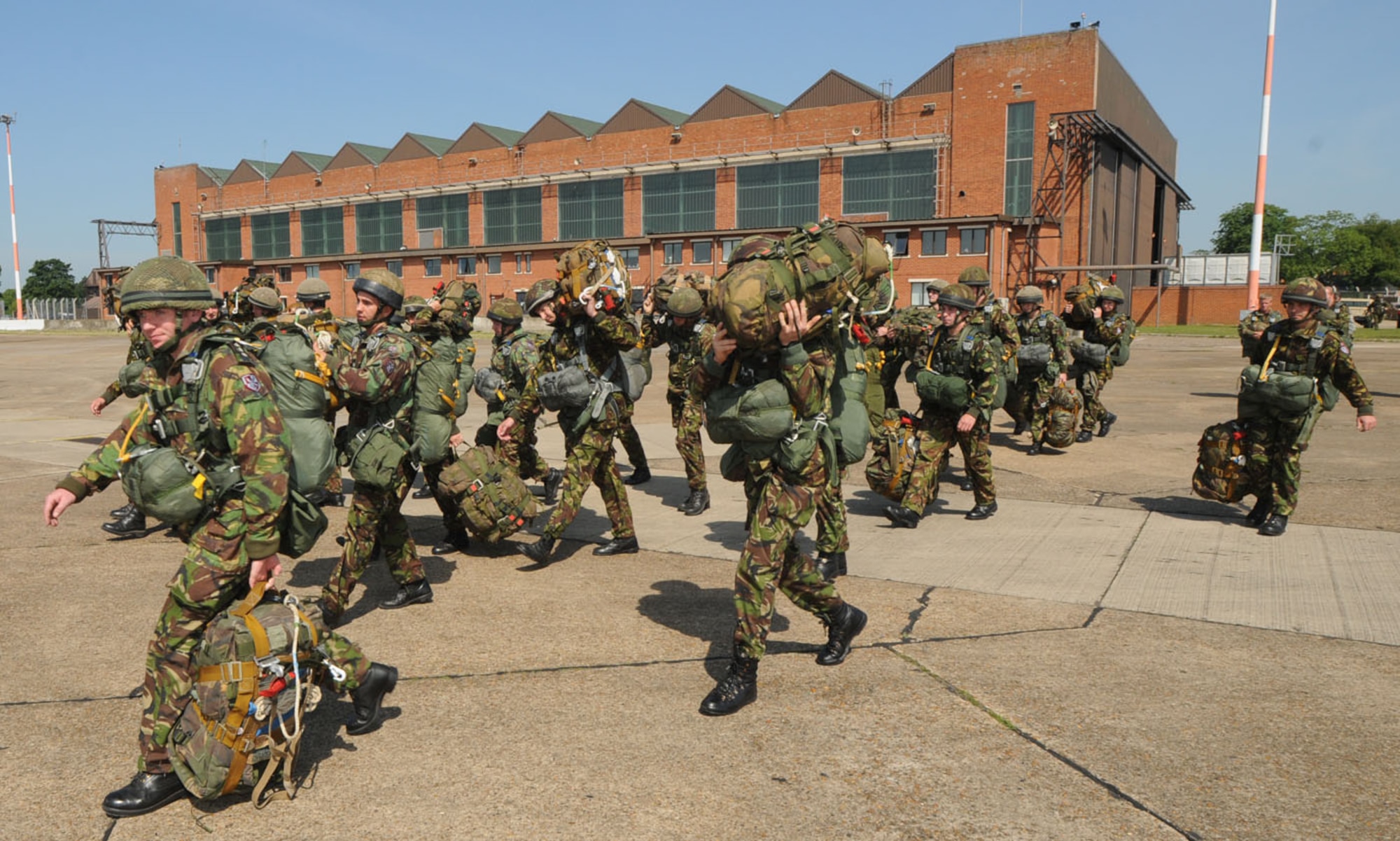 British military members from the 23 Engineer Regiment head out onto the flightline at RAF Mildenhall June 22, to await the arrival of an MC-130H. They were here working with the U.S. Air Force, to earn their American jump wings, and used parachutes belonging to the 321st Special Tactics Squadron. The British regiment jumped with personnel from the 7th Special Operations Squadron, and in return, members from RAF Mildenhall got to jump from a British aircraft June 24. (U.S. Air Force photo/Karen Abeyasekere)