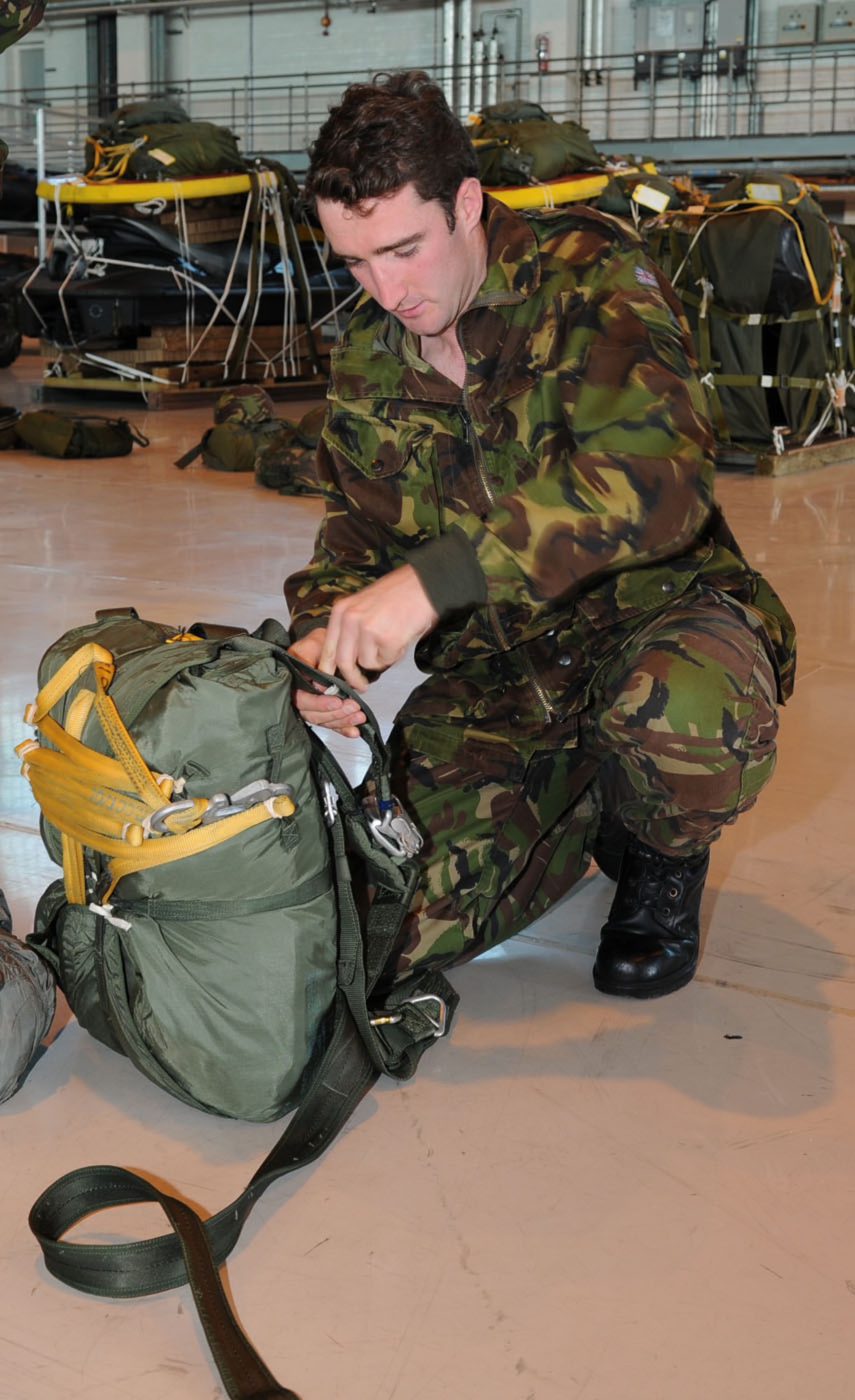Lt. Keith McDougall, 2 Troop commander, 9 Parachute Squadron, Woodbridge, checks his parachute is in order before putting it on June 22. Lieutenant McDougall was at RAF Mildenhall with other British members of the 23 Engineer Regiment, to experience jumping from a U.S. Air Force MC-130H. They used American equipment and parachutes for the jump, and reciprocated when U.S. military members from RAF Mildenhall joined them for a parachute jump from a British aircraft June 24. (U.S. Air Force photo/Karen Abeyasekere)