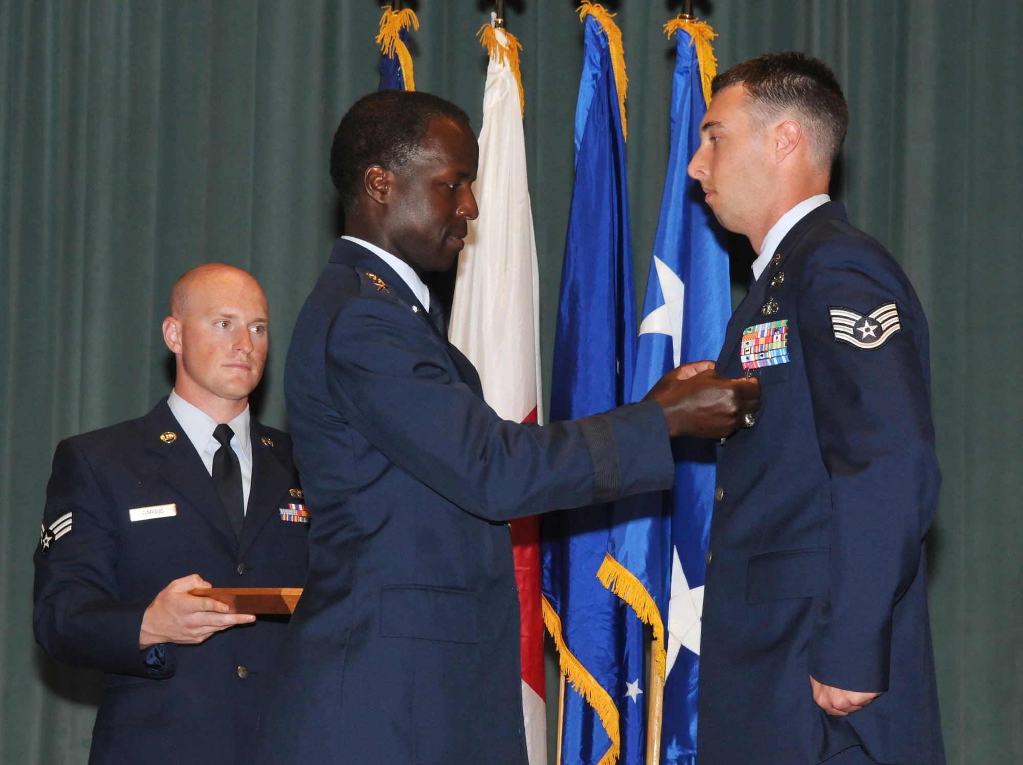 Lt. Gen. Edward Rice Jr., U.S. Forces Japan and 5th Air Force commander, present Staff Sgt. Daniel Sepsey with the Air Force Combat Action Medal June 30 during an enlisted call at the Keystone Theater at Kadena Air Base. General Rice presented Sergeant Sepsey and Senior Airman David Dezwaan, both explosive ordnance technicians with the 18th Civil Engineer Squadron, with AFCAMs for their service while serving with Marines in Helmland Province Afghanistan. (U.S. Air Force photo / Staff Sgt. Christopher Hummel)