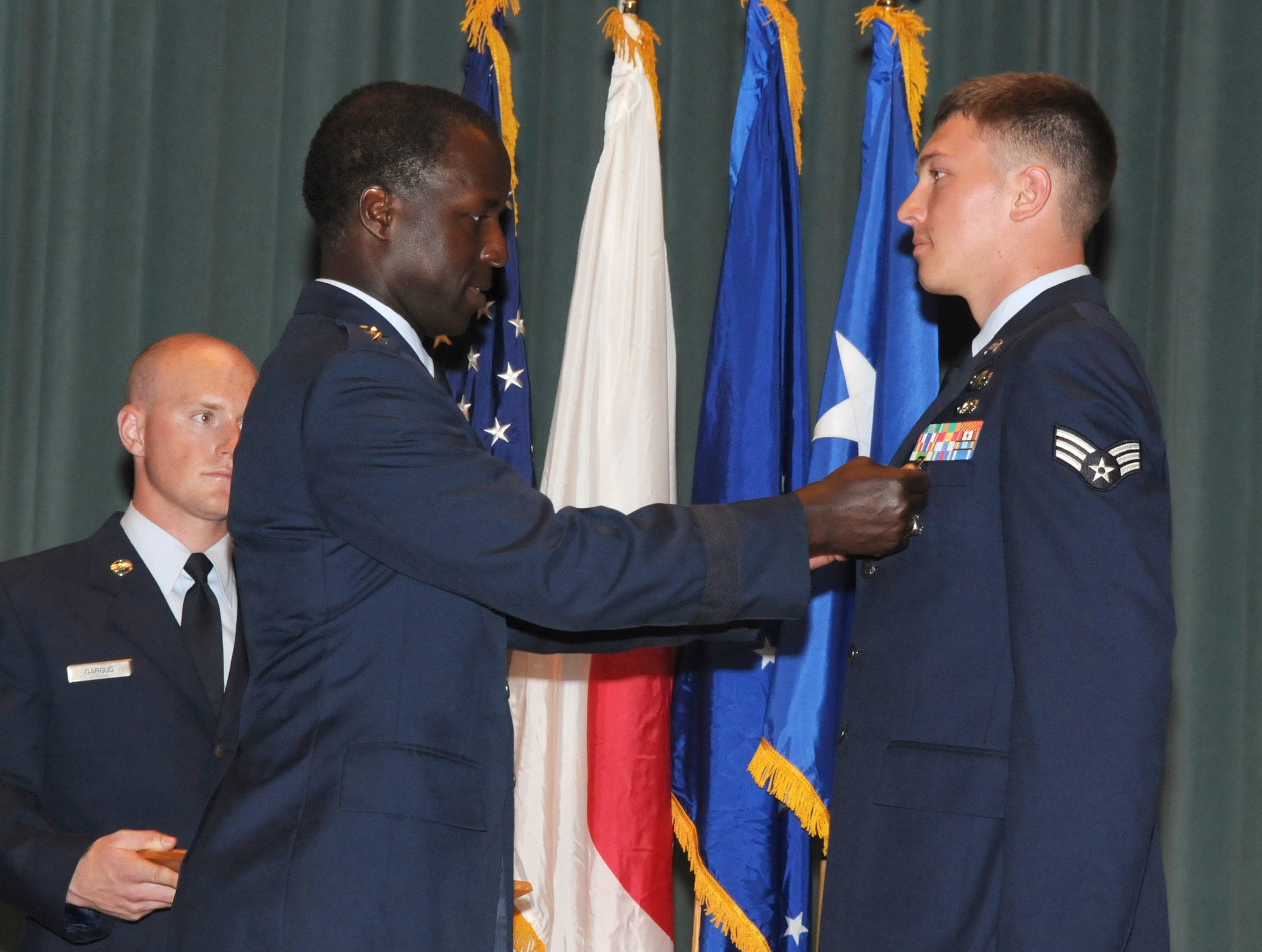 Lt. Gen. Edward Rice Jr., U.S. Forces Japan and 5th Air Force commander, present Senior Airman David Dezwaan with the Air Force Combat Action Medal June 30 during an enlisted call at the Keystone Theater at Kadena Air Base. General Rice presented Airman Dezwaan and Staff Sgt. Daniel Sepsey, both explosive ordnance technicians with the 18th Civil Engineer Squadron, with AFCAMs for their service while serving with Marines in Helmland Province Afghanistan. (U.S. Air Force photo / Staff Sgt. Christopher Hummel)