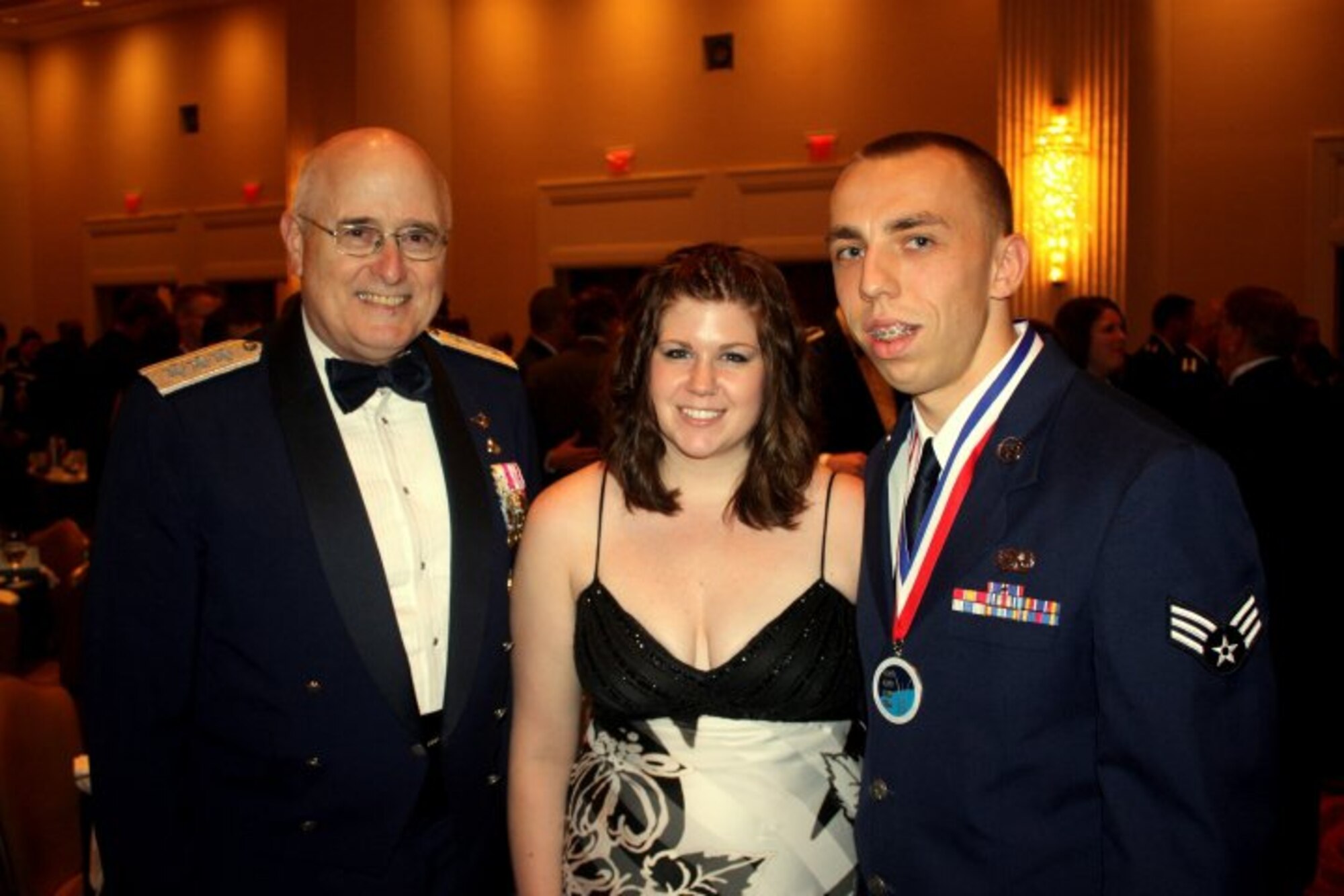 Senior Airman Aaron Leutzen, 721st Aerial Port Squadron and 521st Air Mobility Operations Wing passenger service agent posses with his wife, Jennessa, and Lt. Gen. Loren M. Reno, Headquarters U.S. Air Force deputy chief of staff for logistics after receiving the Air Force Transportation Airman of the Year award May 27 at the Logistics Annual Awards Banquet in Washington, D.C.