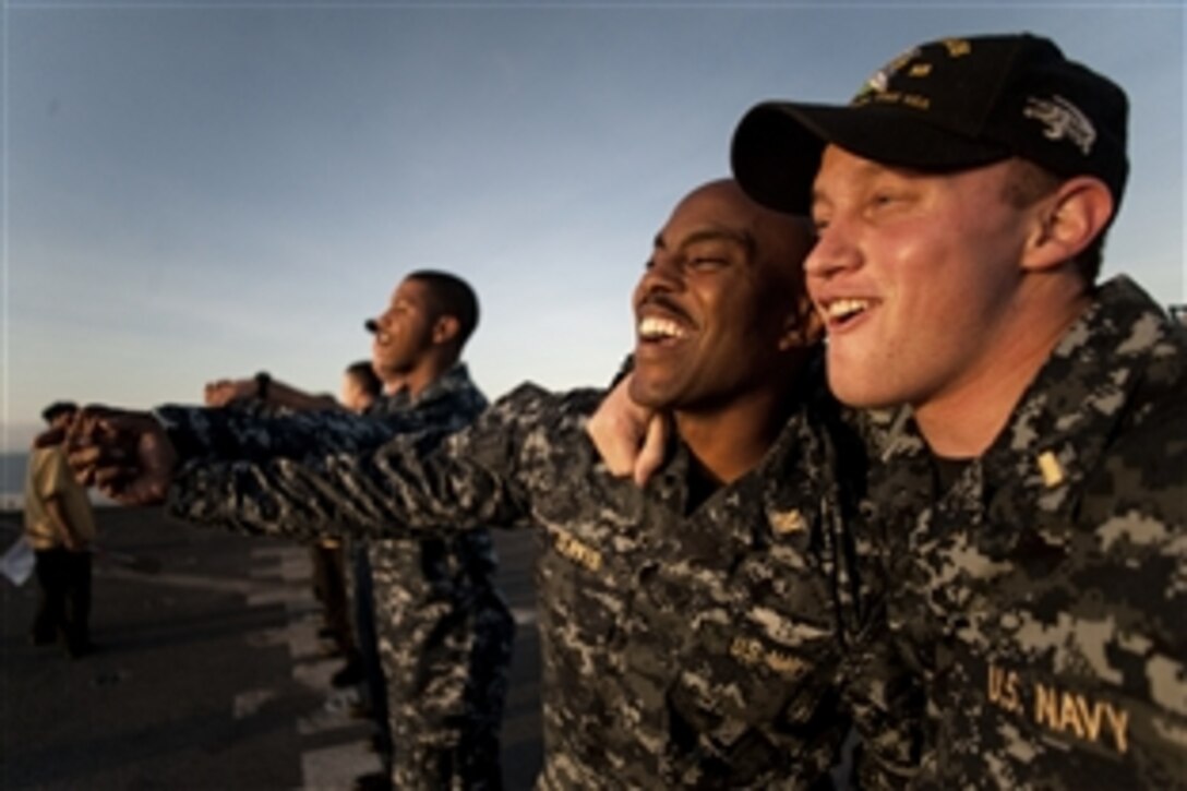 U.S. Navy Ensigns Joseph Davis and Jeremy Sukup, and other sailors and Marines who have not yet crossed the equator, nicknamed "pollywogs," assemble on the flight deck of the USS New Orleans to call for Flipper the dolphin during a traditional ceremony commemorating their first crossing in the Pacific Ocean, June 26, 2010.