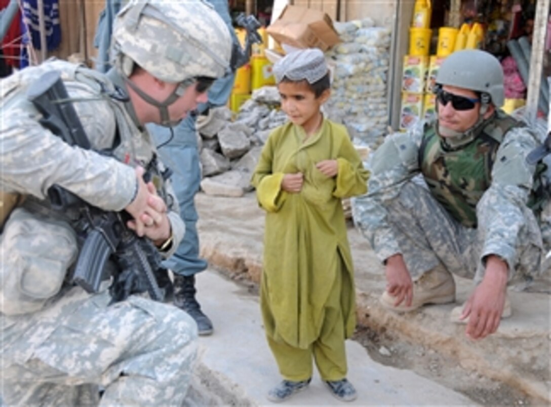 U.S. Army 1st Lt. Matthew Hilderbrand (left) from White Tank, 2nd Platoon, Delta Company, 1st Battalion, 4th Infantry Regiment and an interpreter (right) with the Afghan National Army talk with an Afghan boy during a patrol at a bazaar in the Zabul province of Afghanistan on June 29, 2010.  