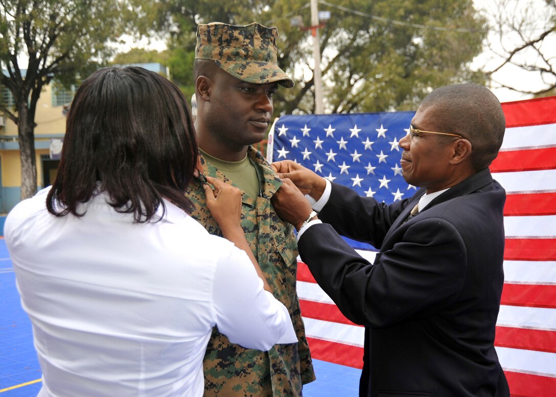 Staff Sgt. Michel Leandre Jr., a Haitian American with Joint Forces Special Operations Component Command recieves his Gunnery Sgt. pins from his uncle and cousin.  The United States and other international military and civilian aid agencies are conducting humanitarian and disaster relief operations as part of Operation Unified Response in the aftermath of the earthquake that hit the area on Jan. 12, 2010.