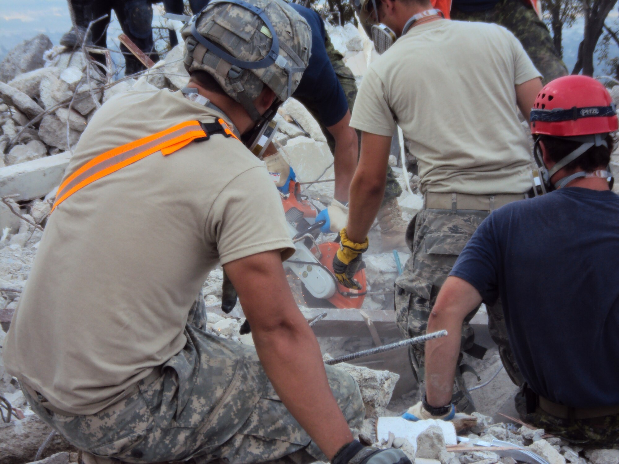 Volunteers cut through heavy debris in the final approach to human remains at Port-au-Prince’s Hotel Montana, which was destroyed during the earthquake Jan. 12. Citizen Airmen from the 67th Aerial Port Squadron volunteered to help excavate the site, where dozen of bodies are still entombed. (Courtesy photo)
