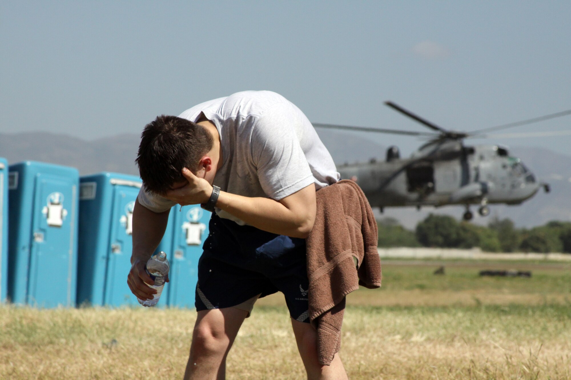 Senior Airman Sterling Broadhead, 67th Aerial Port Squadron, bathes with bottled water outside the tent-city at the Toussaint Louverture International Airport in Port-au-Prince, Haiti, where he and his fellow Citizen Airmen lived for more than a month. (Courtesy photo)
