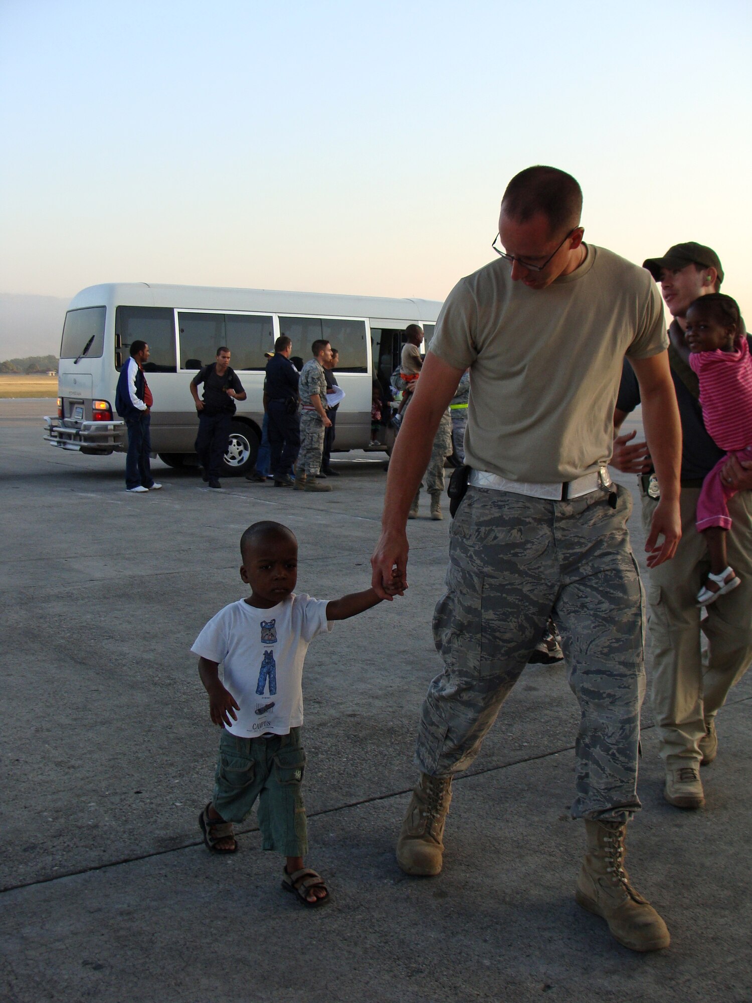 Tech. Sgt. Justin Adams, 67th Aerial Port Squadron, guides a Haitian boy to the aircraft that will take him to his new home in the U.S. (Courtesy photo)