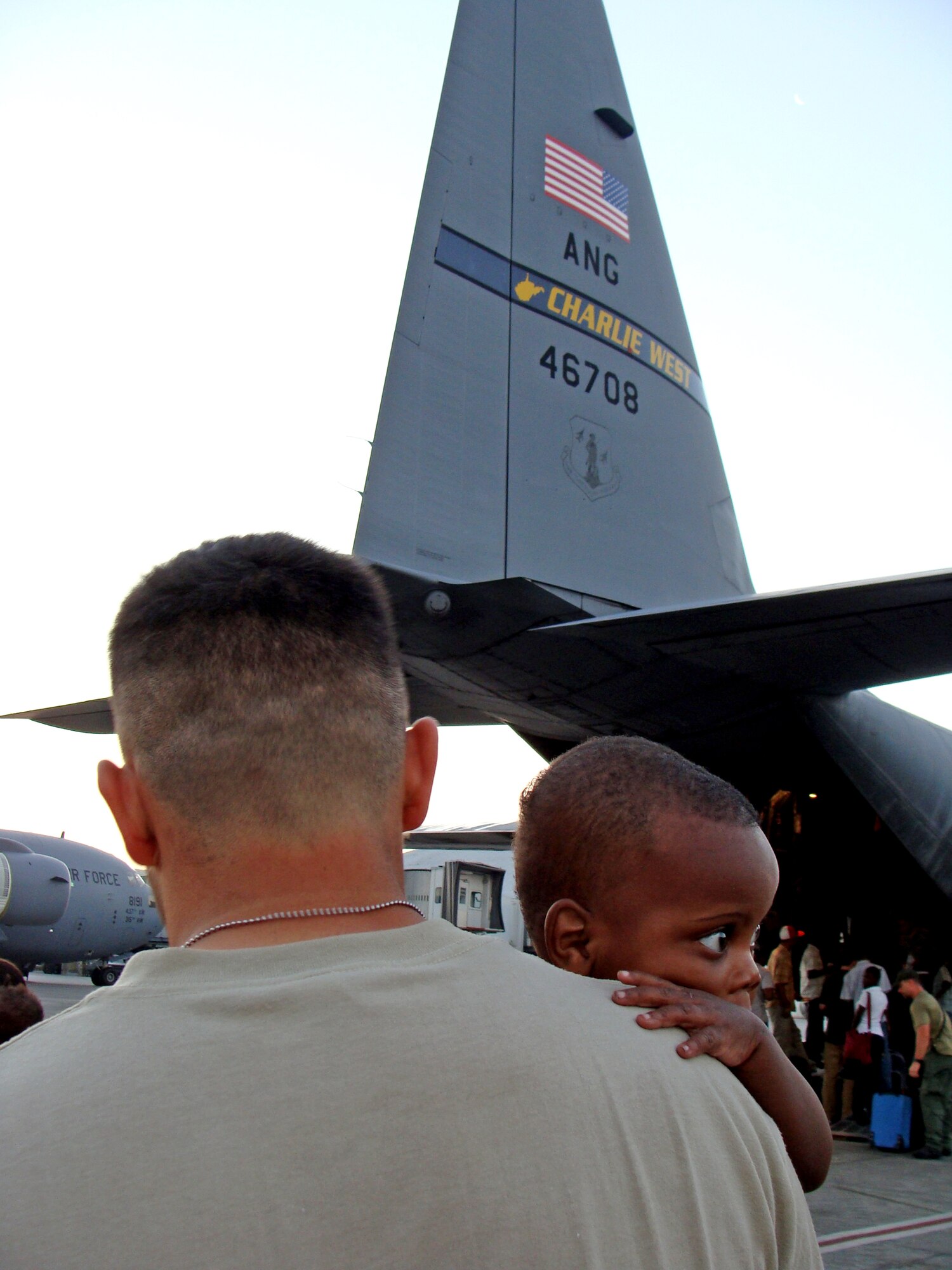 Tech. Sgt. Cody De Los Reyes, 67th Aerial Port Squadron, consoles a Haitian orphan before the little one boards an aircraft headed for the U.S. Sergeant De Los Reyes and 14 other Air Force Reservists from the 419th Fighter Wing at Hill Air Force Base, Utah, deployed to Haiti for just over a month to help stabilize airfield operations in the earthquake-stricken country. (Courtesy photo) 