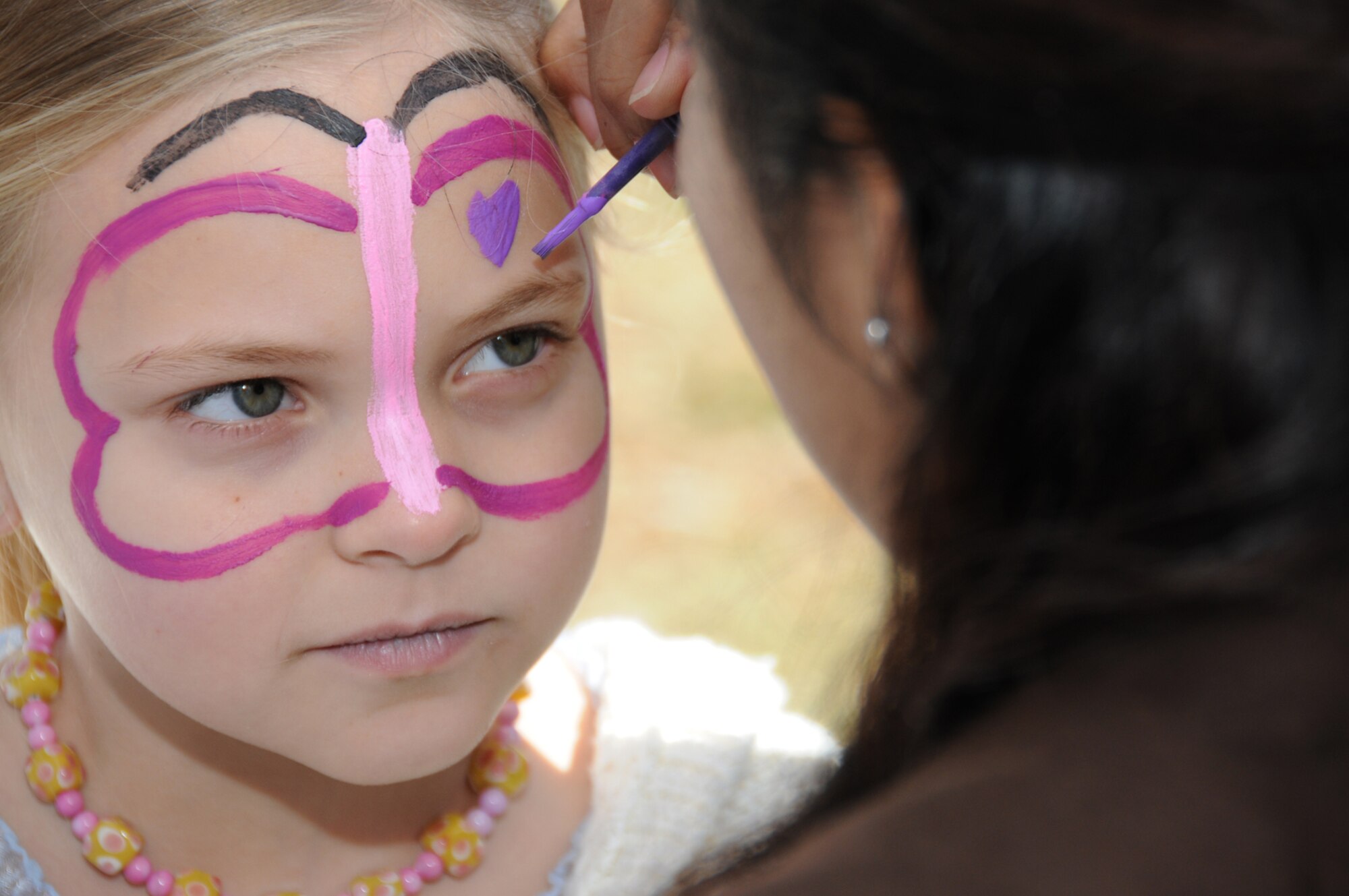 Airman Tiffany Degracia, 334th TRS, paints the face of Nina Gestring, 7, during the Mardi Gras festivities on Feb. 16 in Biloxi.  The airman and family readiness center hosted a cookout for the family members of Keesler's deployed Airmen at the Biloxi Town Green which is along the route for the Gulf Coast Carnival Association Mardi Gras parade.  Nina is the daughter of Master Sgt. Ken and Corina Gestring.  Sergeant Gestring, 81 MSGS, is currently on a one-year deployment to South West Asia.  (U.S. Air Force photo by Kemberly Groue)


