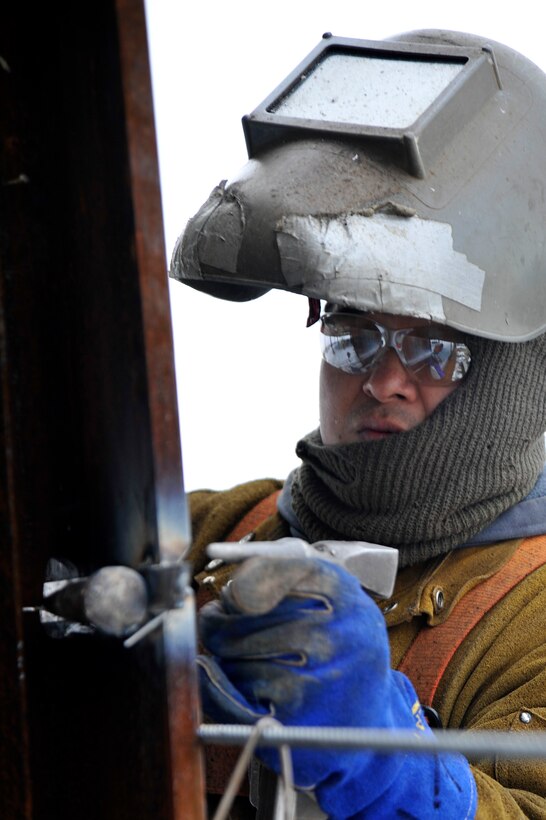 A welder from Miscellaneous Metals Inc. uses a chipping hammer to clear the slag off of a weld while welding I-Beams together at the new William A. Jones III headquarters building Feb. 23, 2010 at Joint Base Andrews, Md.  These beams will be the main support beams for the entire building. The $114.2 million building is scheduled to be completed next year. (U.S. Air Force photo by Airman 1st Class Perry Aston) (Released)