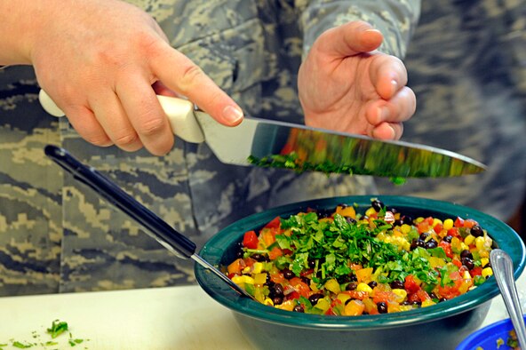 ELLSWORTH AIR FORCE BASE, S.D. -- Senior Airman Sarah Greear, 28th Medical Operations Squadron diet therapy technician, places chopped cilantro into a mixing bowl during a heart-healthy recipe demonstration, Feb. 26. The Health and Wellness Center hosted the demonstration to inform the base populace about various recipes to facilitate a healthy lifestyle. (U.S. Air Force photo/Airman 1st Class Matthew Flynn)