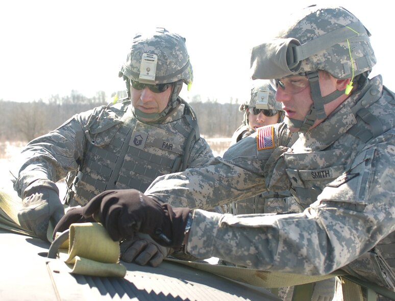 Master Sgt. Paul Fair, left, of the 188th Fighter Wing, and Spec. Dustin Davis of Poteau, Okla., right, stow a tow strap on a humvee hood in preparation for an exercise in tactical vehicle recovery during training Feb. 16 at Camp Atterbury, Ind.  Both Guardsmen are members of the Agriculture Development Team of the Arkansas National Guard. Lt. Col. David Sheely, 188th Fighter Wing Maintenance Squadron commander, is the team leader for the agriculture specialists. Fair is the assistant chief of the 188th Civil Engineering Squadron's Fire Department. Tech Sgt. Justin Mankins, a firefighter with the 188th Fire Department, is also a member of the ADT. The team of approximately 60 Soldiers and Airmen will be deploying to Afghanistan in March to assist farmers in that nation with advanced farming practices and education.  (Photo by Lt.Col. Keith Moore/Arkansas ADT Public Affairs Officer) 