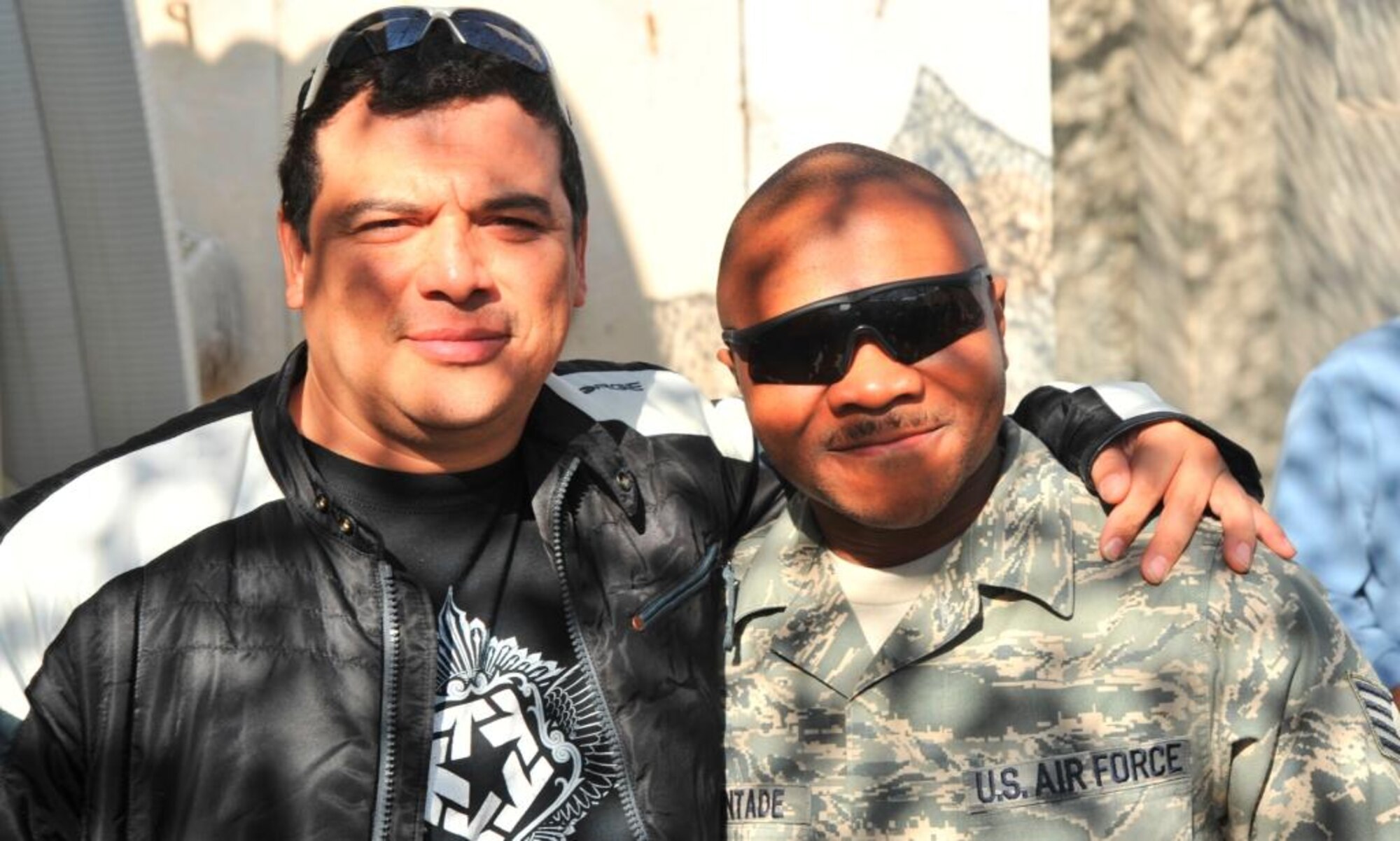 SATHER AIR BASE, Iraq -- Staff Sgt. Azeez Oguntade, Headquarters Air Combat Command Protocol, poses with comedian Carlos Mencia at a USO Tour for the Troops event. Sergeant Oguntade is responsible for the transportation of distinguished visitors and celebrities in the area of responsibility. (Courtesy photo)