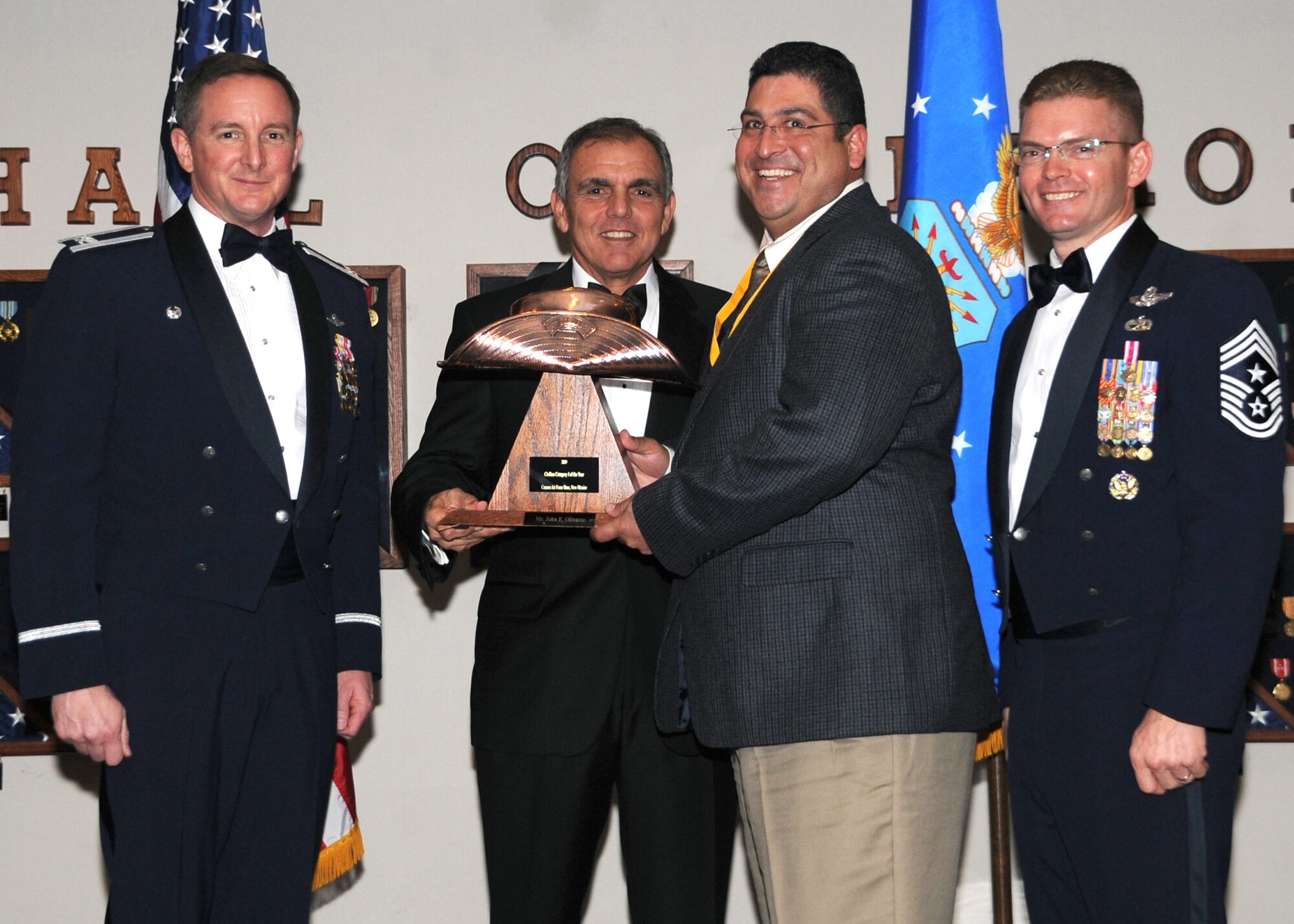 John Olivaras, 27th Special Operations Mission Support Group, receives the Category III Civilian of the Year award from (left) Col. Stephen Clark, 27th Special Operations Wing commander, Retired Air Force Maj. Gen. Richard Comer, and (right) Chief Master Sgt. William Turner, wing command chief. The wing's top Airmen and civilians were recognized at the annual awards dinner at The Landing Zone Feb. 20 at Cannon Air Force Base, N.M. (U.S. Air Force photo by Airman 1st Class Maynelinne De La Cruz) 