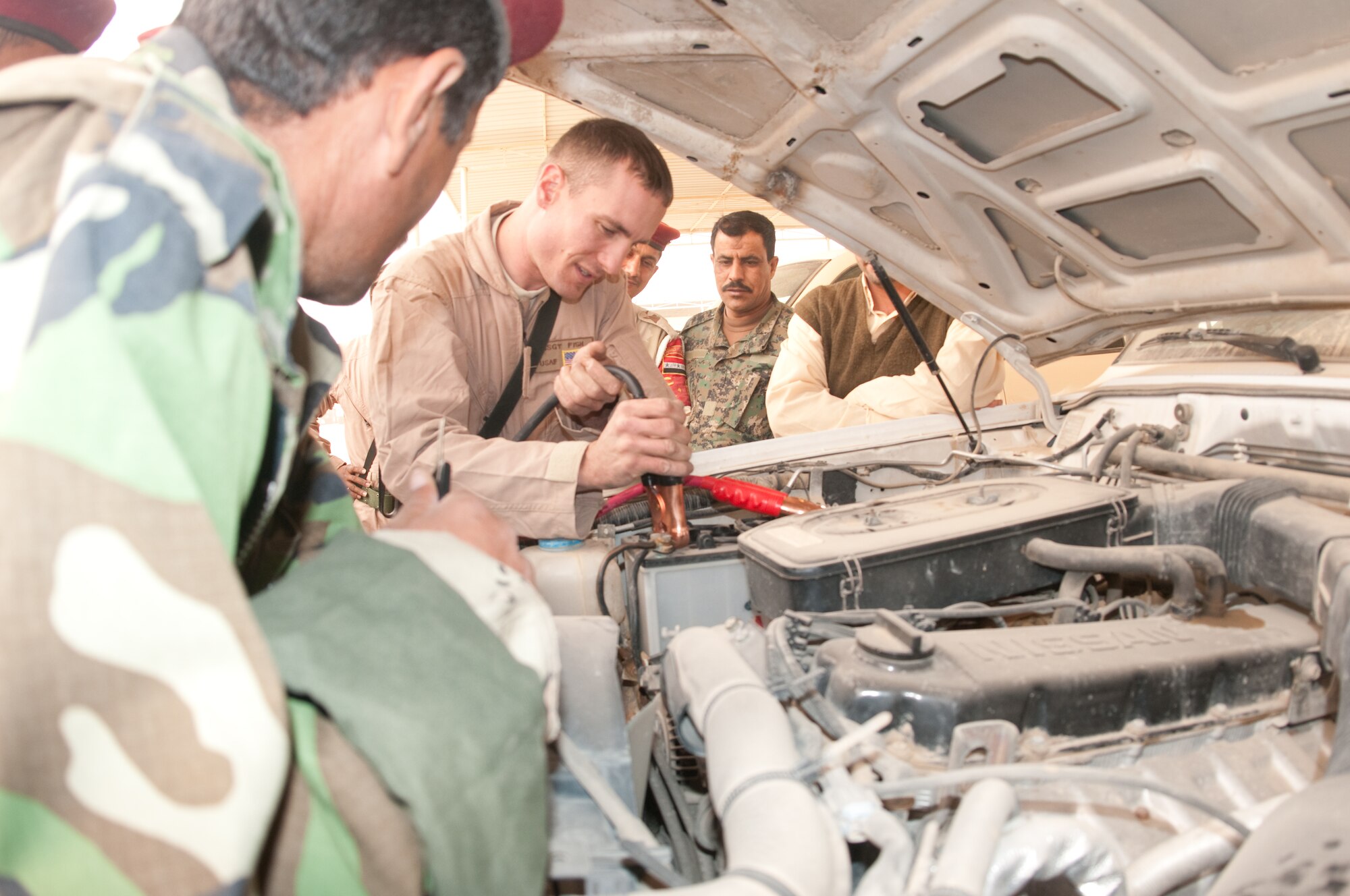 U.S. Air Force Staff Sgt. Giles Fish, 407th Expeditionary Logistics Readiness Squadron, Ali Base, Iraq deployed from 19th Logistics Readiness Squadron, Little Rock AFB, Ark., demonstrates to eager Iraqi Army personnel how to sequentially place the jumper cables on to a charged battery during a training course given by the Logistics Military Advisory Team at Camp Ur, Iraq, Feb. 22, 2010. Sgt Fish is from Great Falls, Mont. (Photo by Senior Master Sgt. Elizabeth Gilbert/released)