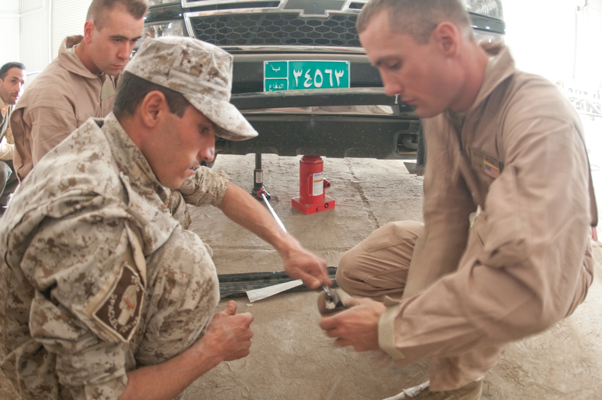U.S. Air Force Staff Sgt. Giles Fish, 407th Expeditionary Logistics Readiness Squadron, Ali Base, Iraq deployed from 19th Logistics Readiness Squadron, Little Rock AFB, Ark., helps out an Iraqi Army personnel as they prepare to elevate the truck during  a training course given by the Logistics Military Advisory Team at Camp Ur, Iraq, Feb. 22, 2010. Sgt Fish is from Great Falls, Mont. (Photo by Senior Master Sgt. Elizabeth Gilbert/released)