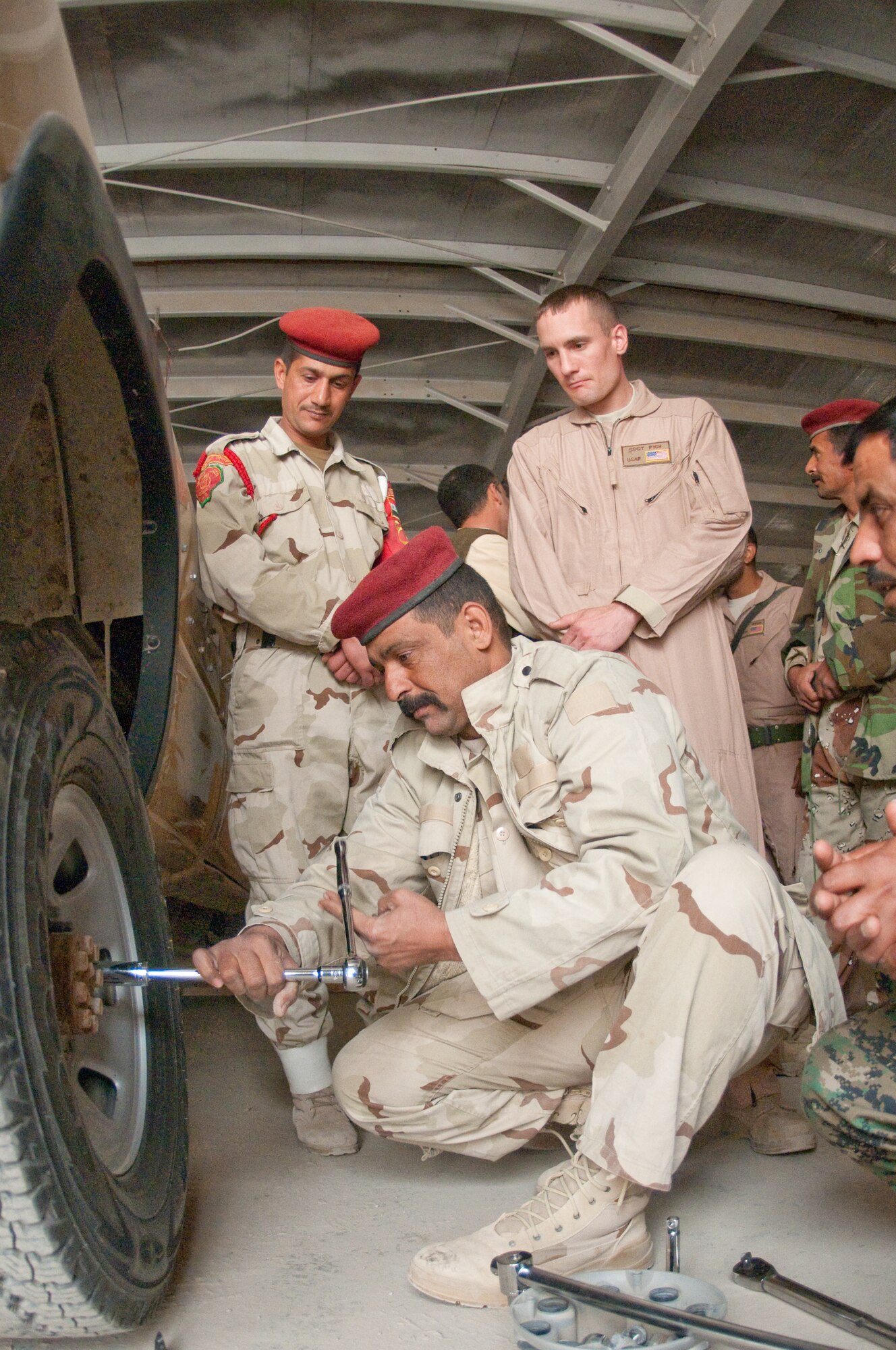 U.S. Air Force Staff Sgt. Giles Fish, 407th Expeditionary Logistics Readiness Squadron, Ali Base, Iraq deployed from 19th Logistics Readiness Squadron, Little Rock AFB, Ark., observes Iraqi Army personnel as he supervises their tire change during a training course given by the Logistics Military Advisory Team at Camp Ur, Iraq, Feb. 22, 2010. Sgt Fish is from Great Falls, Mont. (Photo by Senior Master Sgt. Elizabeth Gilbert/released)