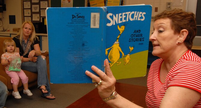 Nancy Speer (left), a Kadena Elementary School literacy specialist, reads "Sneeches" by Dr. Seuss to Tayson, Tatum and Kara Barney during the school's birthday tribute to the famous author March 2. Dozens of students and parents read books, played computer learning games and ate green eggs and ham. (Air Force photo/Staff Sgt. Jason Lake)