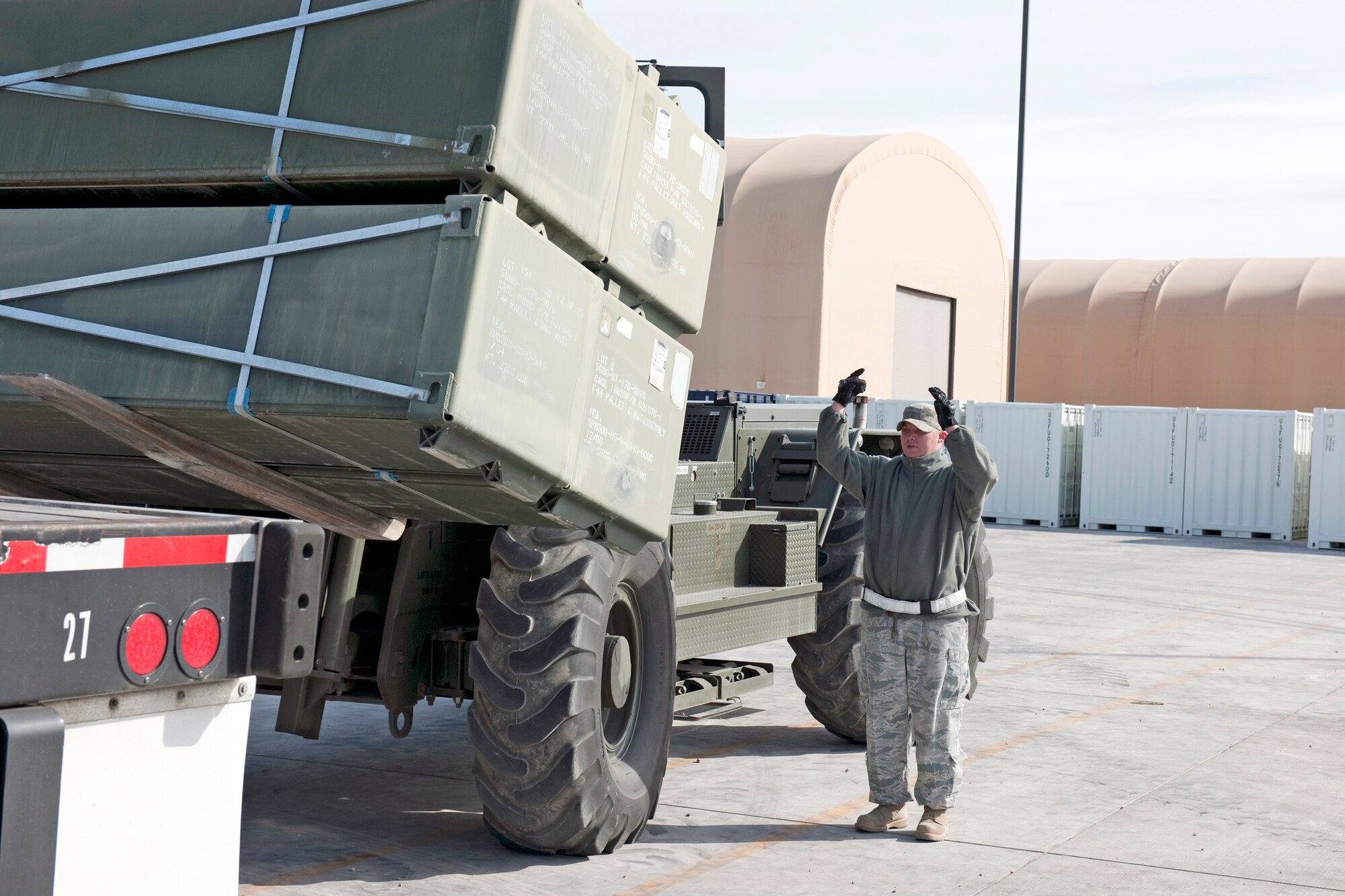 Senior Airman Scottie Owens ground-guides a 13,000 pound loader carrying nearly 11,000 pounds of AM-2 matting onto a flatbed trailer Feb. 24, 2010, at Holloman Air Force Base, N.M. Airman Owens is assigned to the 49th Materiel Maintenance Support Squadron. The 49th MMSS is deploying 480,000 square feet of the matting that will be assembled to create airstrips supporting joint and coalition forces throughout Afghanistan. (U.S. Air Force photo/Staff Sgt. Joe Laws)