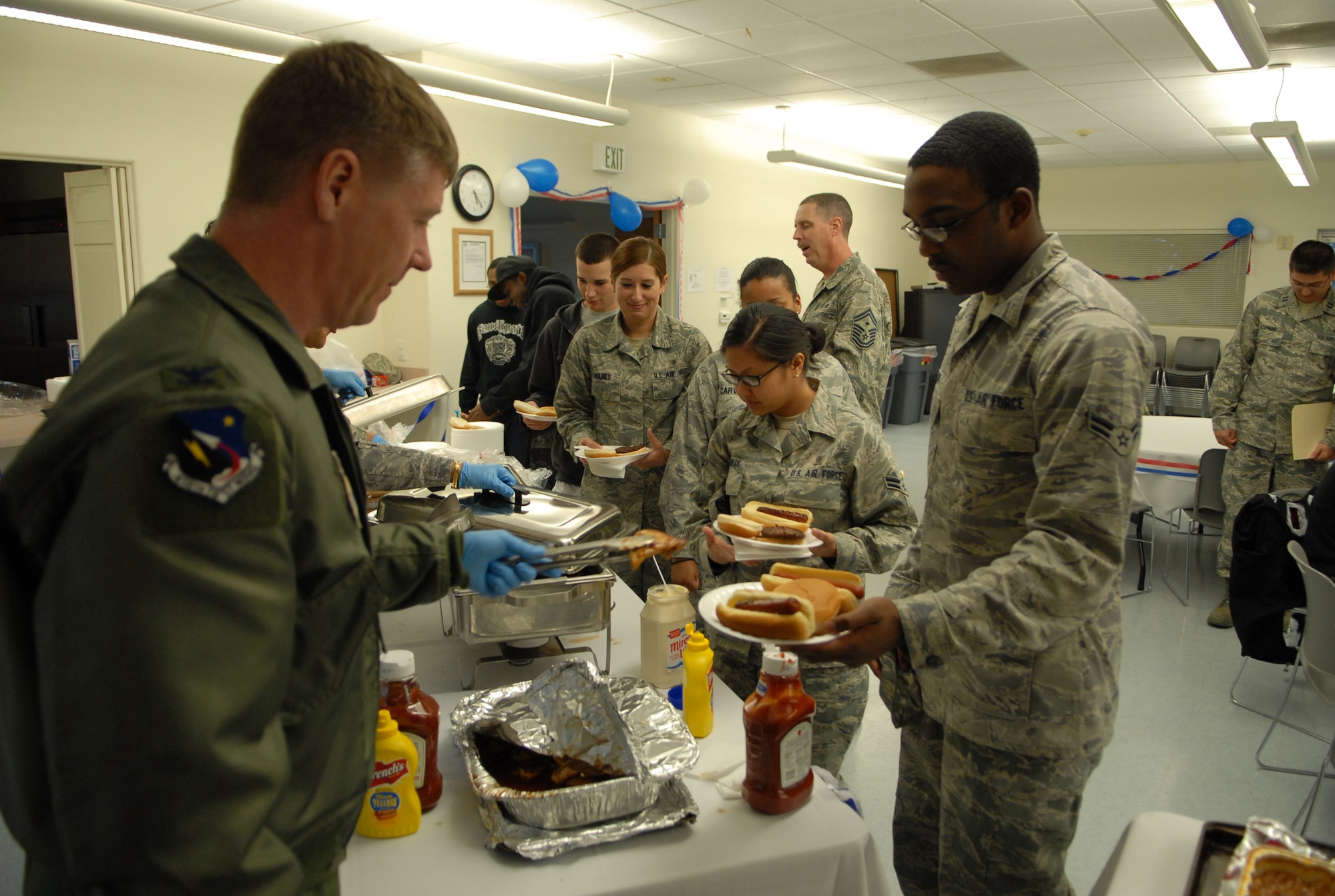 A line of Airmen headed by Airman 1st Class javoris Sapp, 95th Aerospace Medicine  Squadron Bioenvironmental Flight, receive food from base leadership during the Dorm Dinner in the Chapel 1 Annex here Feb. 24. The dinner was hosted by Edwards Company Grade Officers Council for all Edwards dorm residents. (Air Force photo/Airman 1st Class William O'Brien)